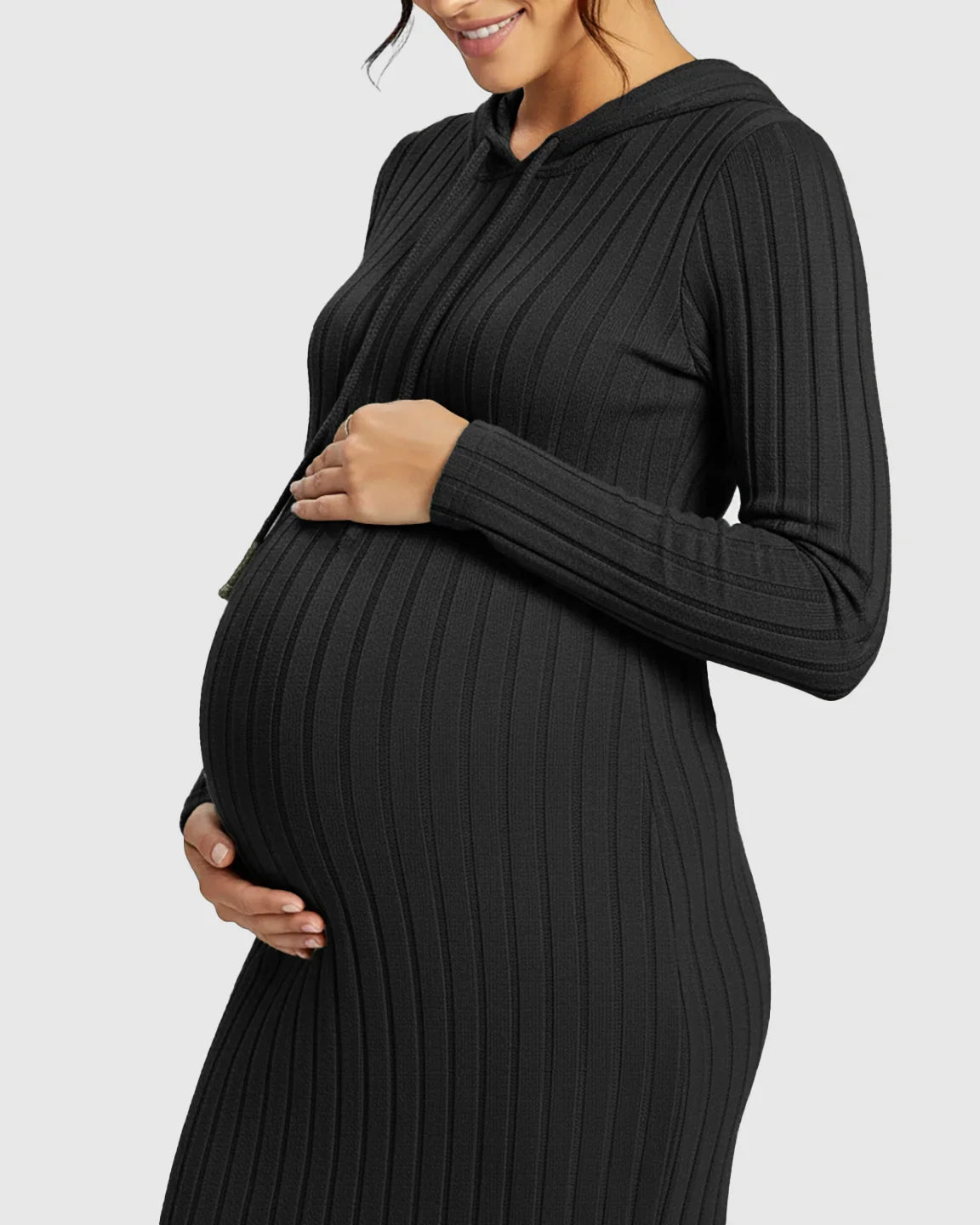 Pregnant woman in a black ribbed bodycon hooded maternity midi dress, gently holding her bump.