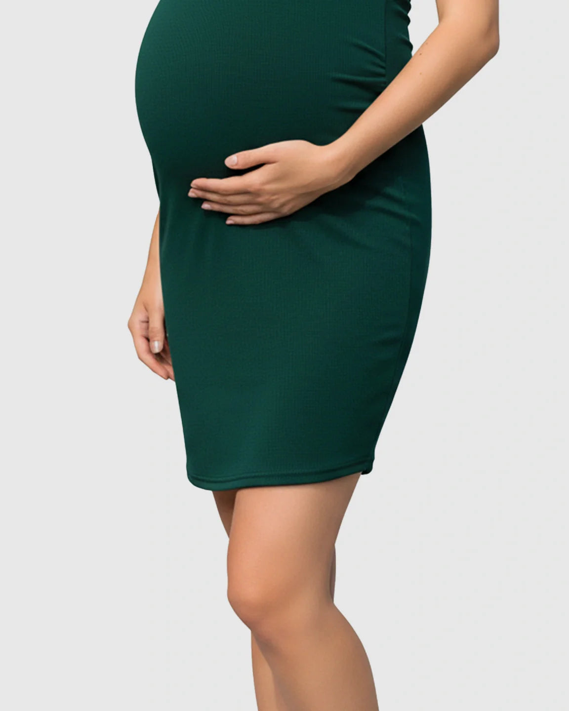 Pregnant woman in a dark green ribbed bodycon maternity dress with side ruching, scoop neck.
