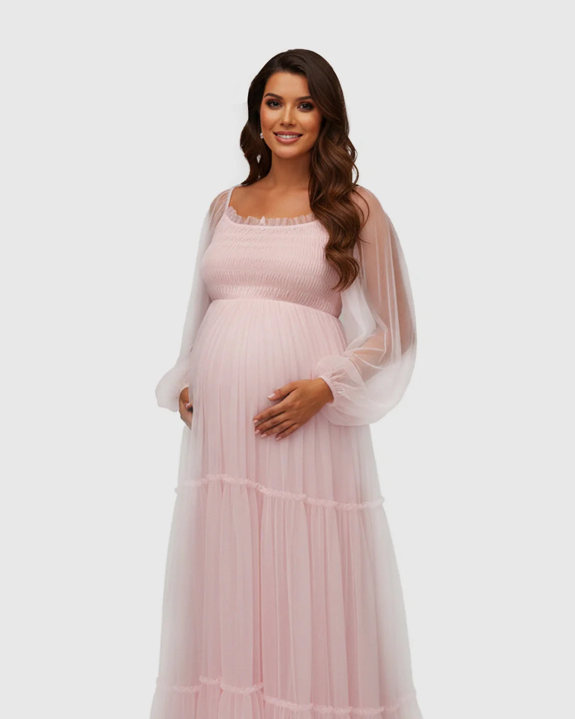 Smiling pregnant woman in a pink tiered tulle maternity gown with lantern sleeves.