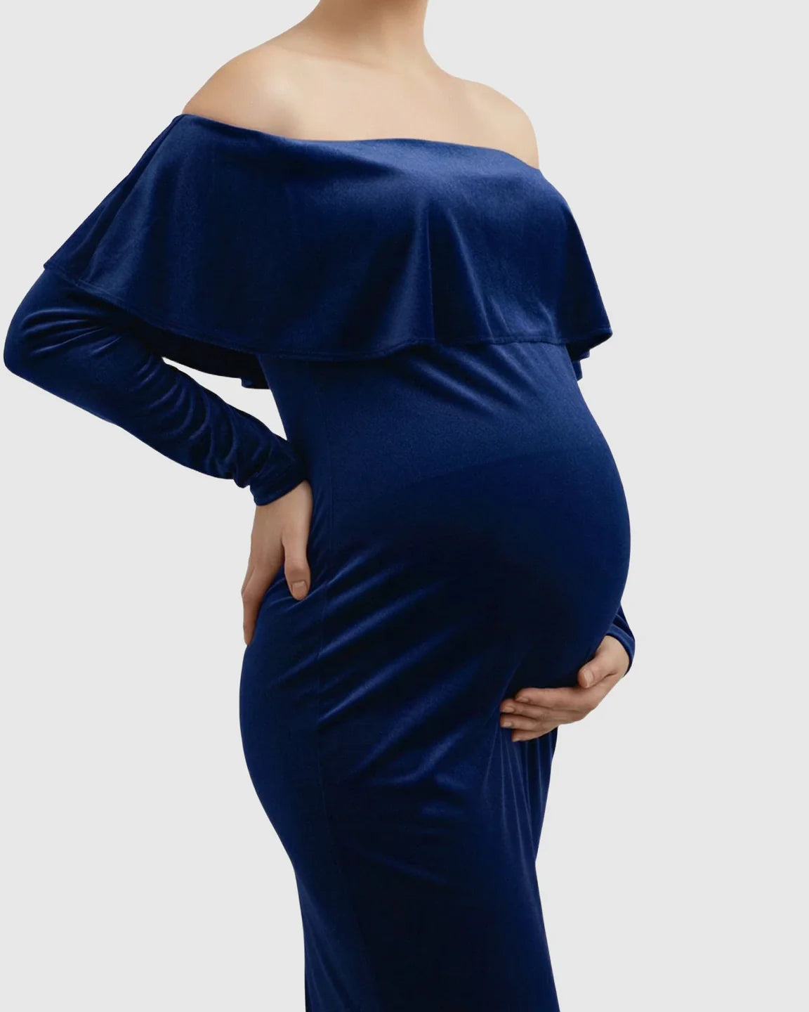 Navy velvet off-shoulder maternity photoshoot gown, fitted with a flowing train, highlighting a pregnant belly.