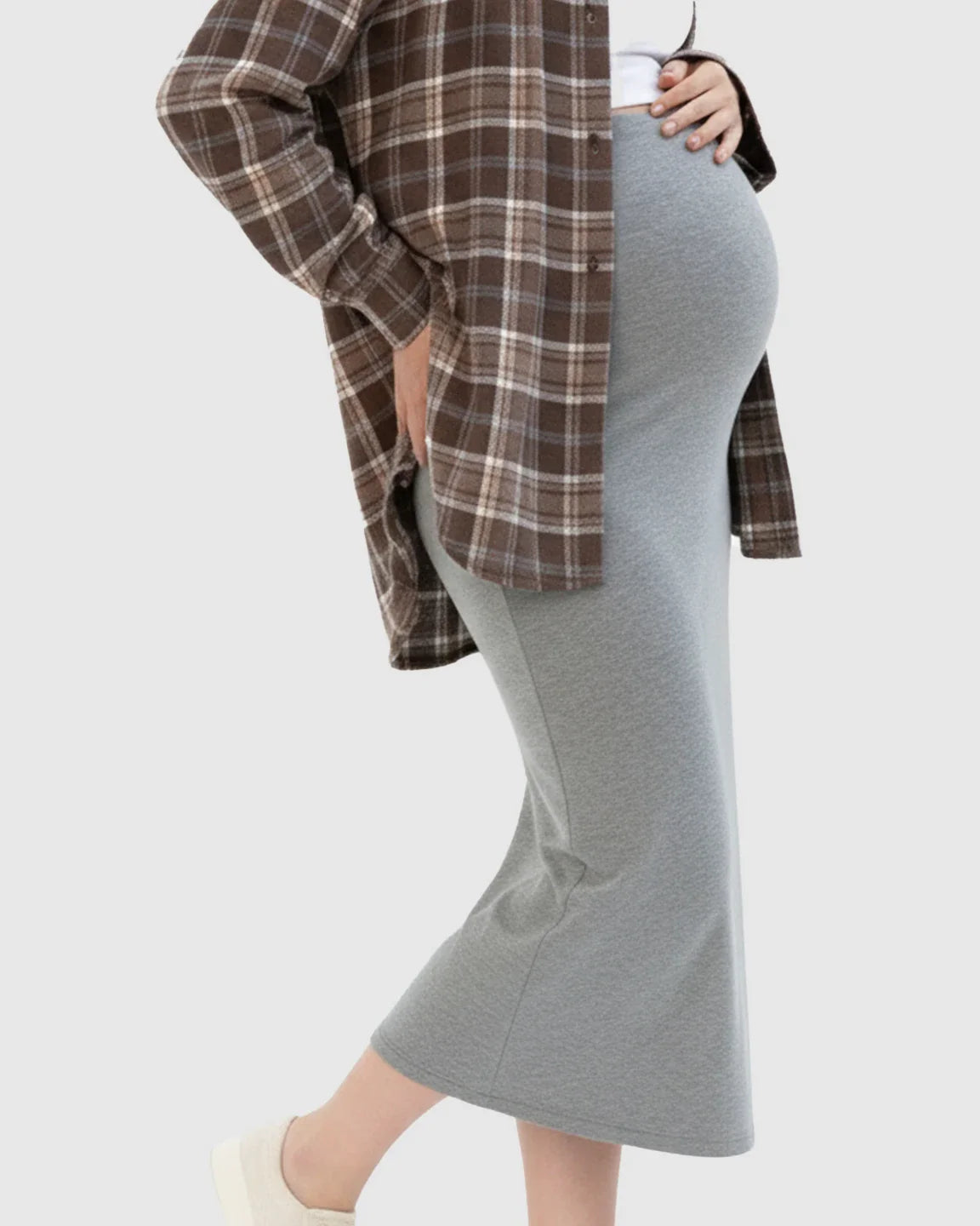 Pregnant woman in a gray midi skirt and brown plaid shirt, highlighting the comfortable, stretchy fit.