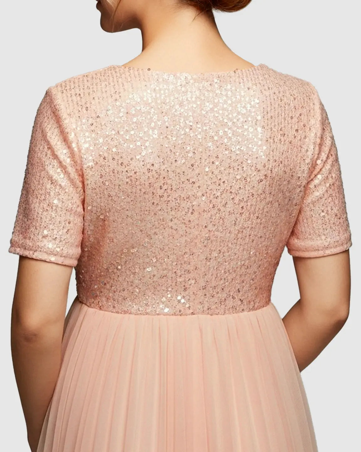 Back view of a pink sequin A-line maternity evening gown with short sleeves and a flowing skirt.
