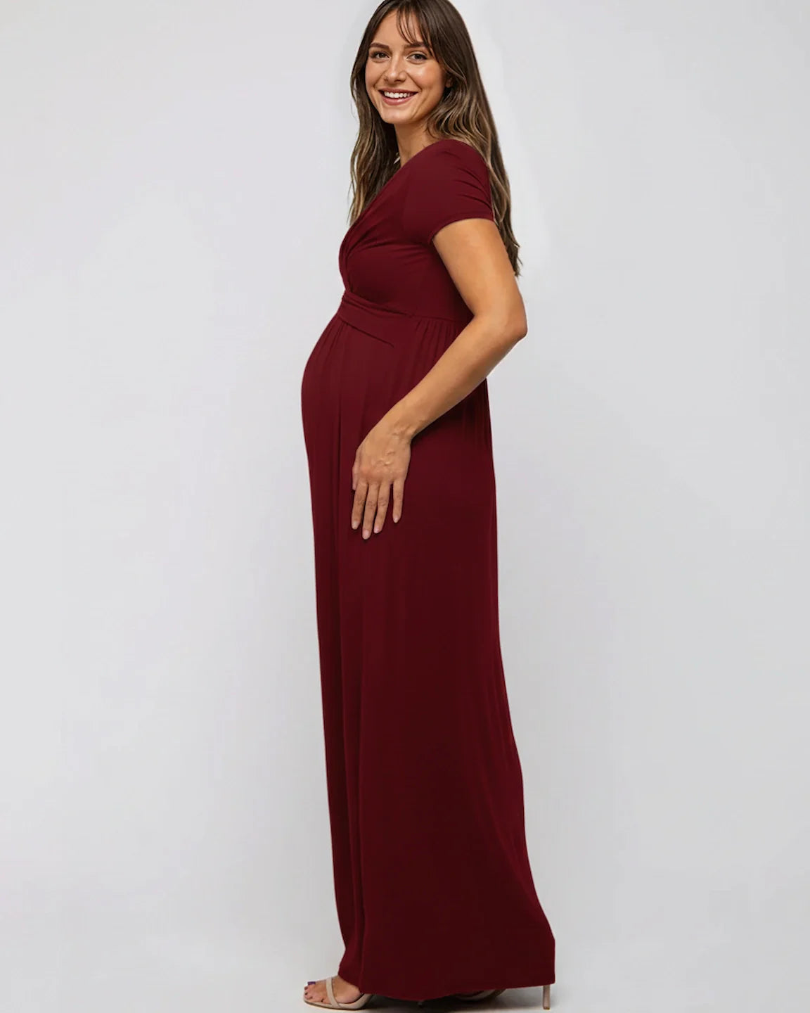 Smiling pregnant woman in a burgundy Twist Front Draped Maternity Nursing Maxi Dress.