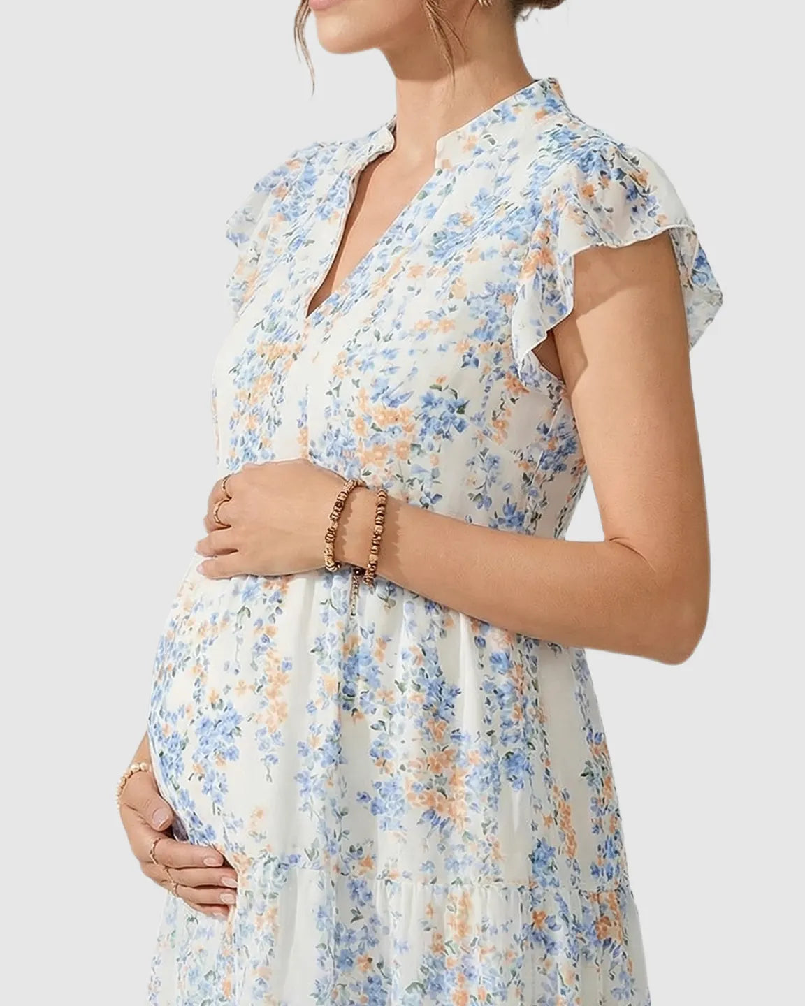 White floral A-line maternity dress with blue and orange flowers, flutter sleeves, and a tiered skirt.