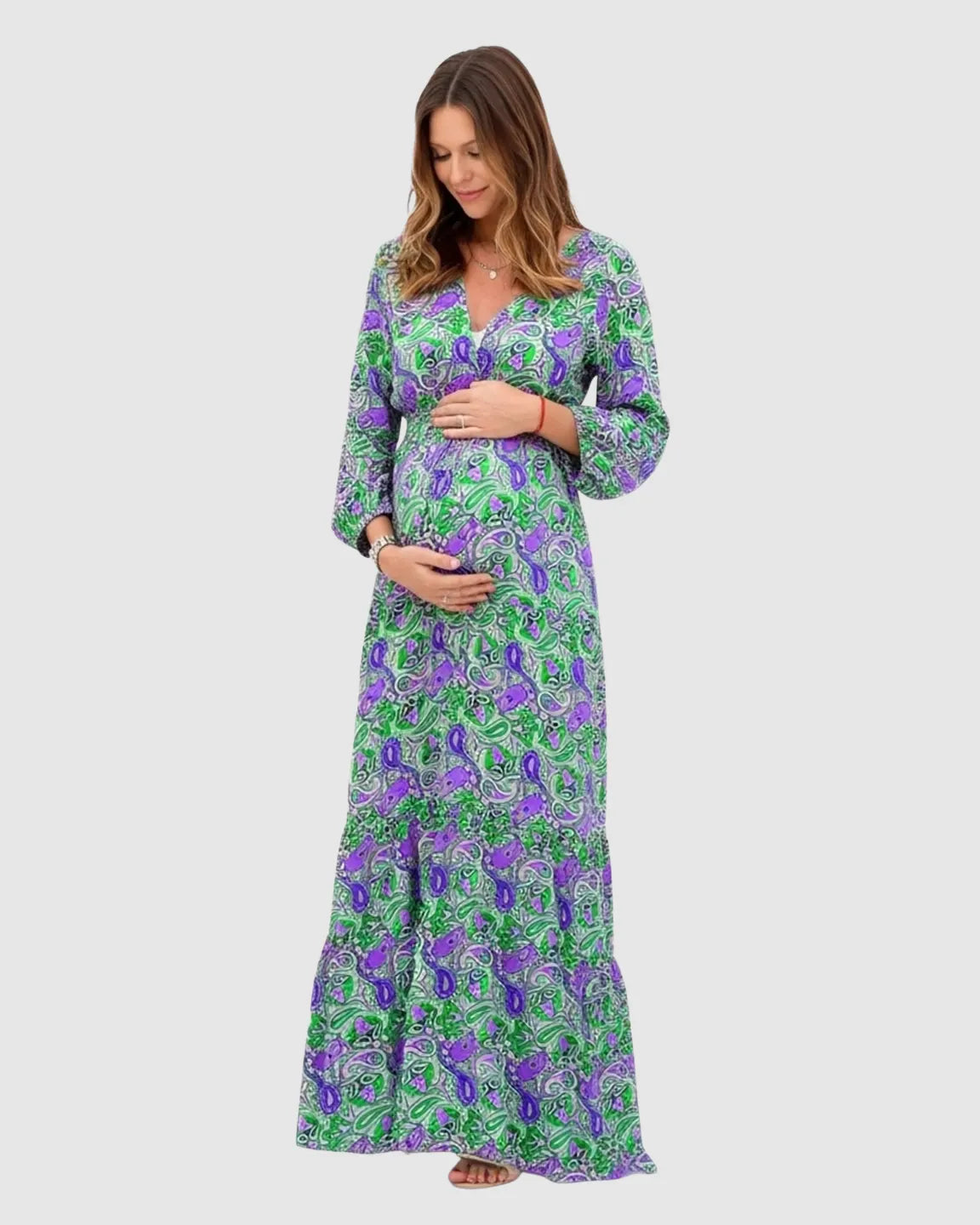 Pregnant woman in a green and purple boho paisley flowy maxi dress with an adjustable tie waist.