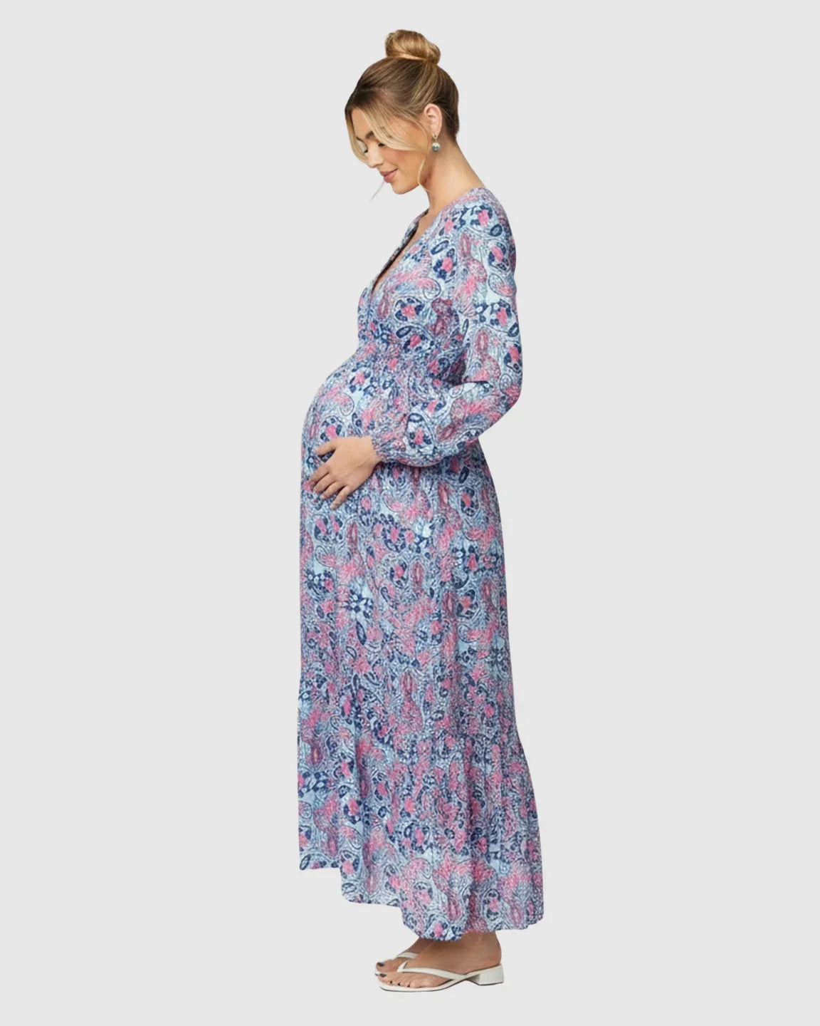 Pregnant woman in a blue and pink paisley flowy maxi dress with long sleeves and a V-neck.