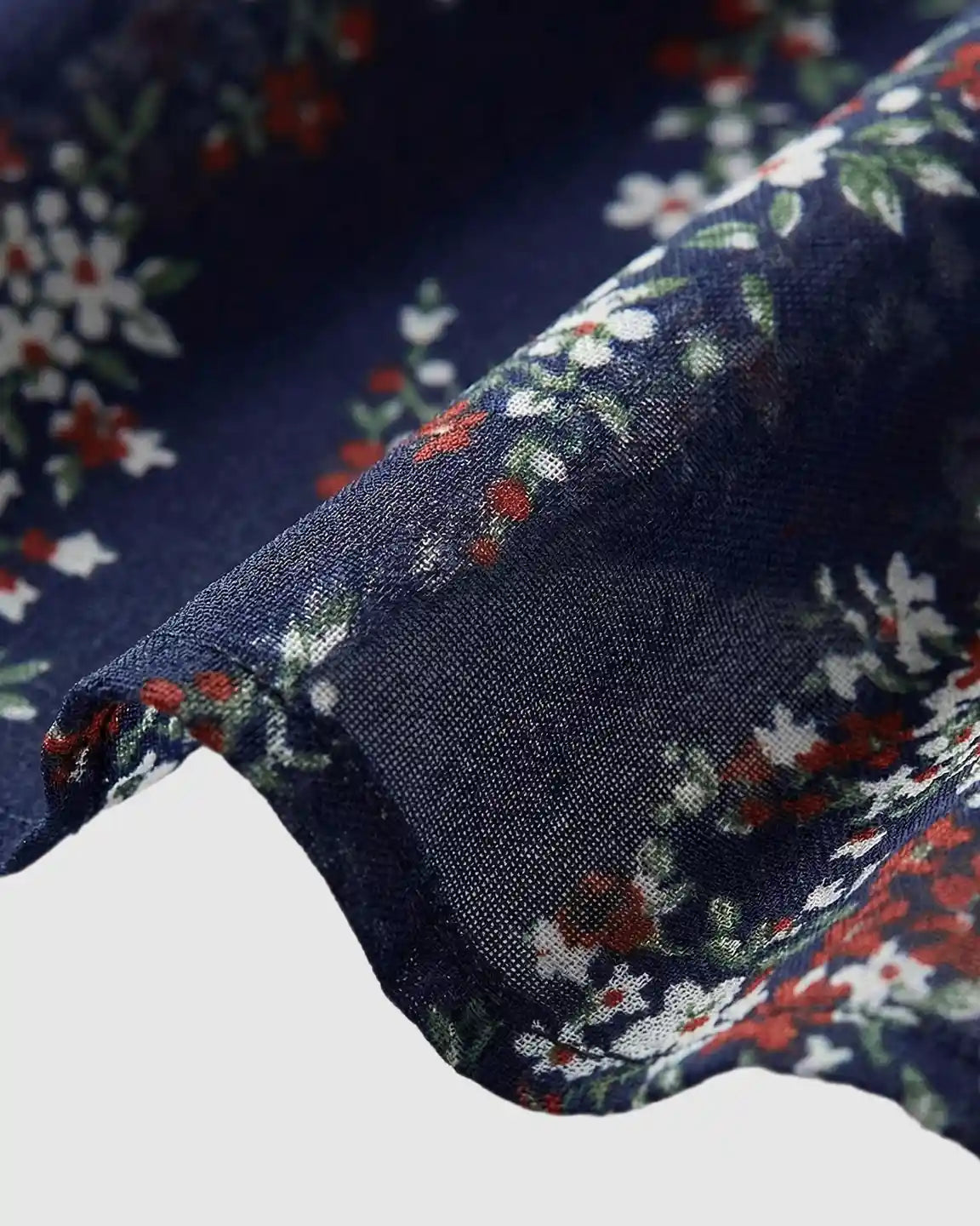 Close-up of navy chiffon maternity dress fabric with white and red floral print, showing flutter sleeve detail.