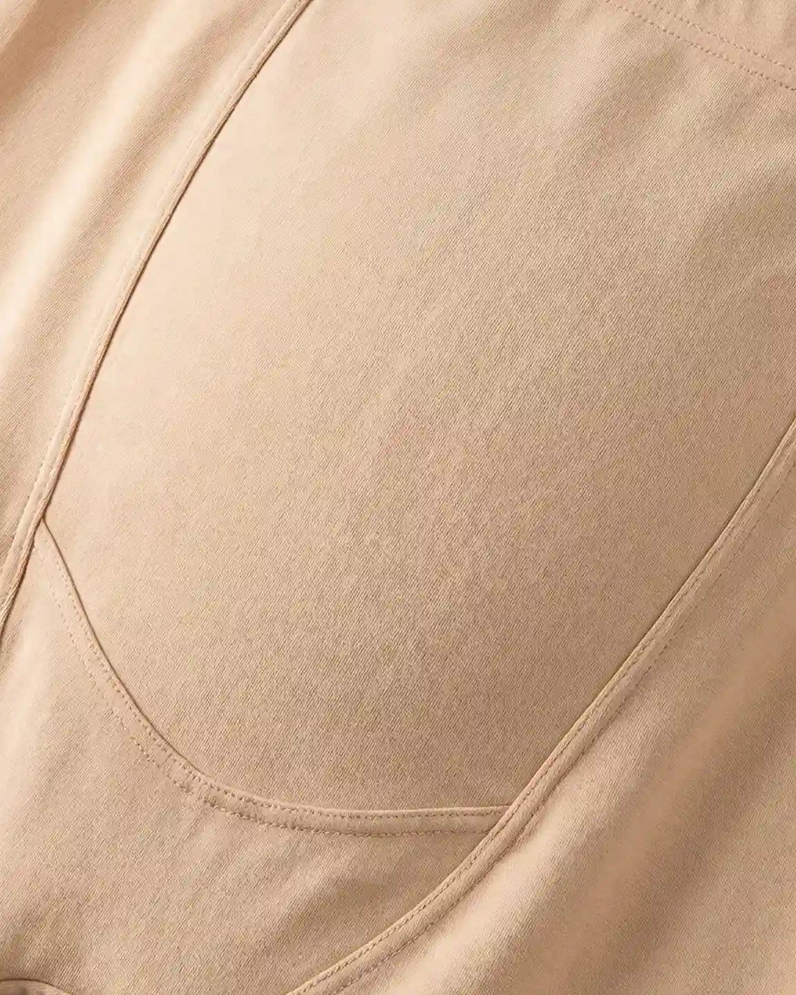 Close-up of beige fleece-lined over-bump maternity leggings with visible stitching and soft fabric texture.