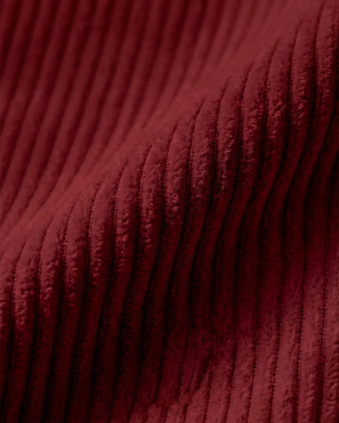 Close-up of rich burgundy corduroy fabric, showcasing its soft texture and ribbed design.