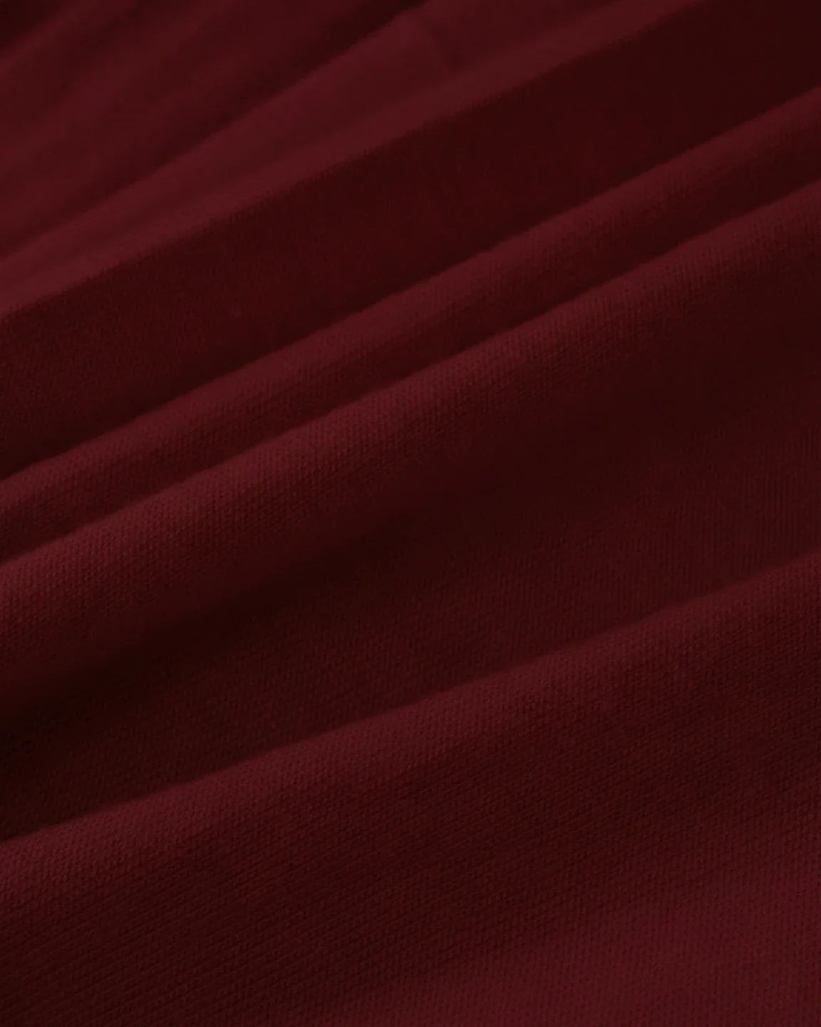Close-up of a rich burgundy, soft, stretchy fabric, likely for a draped maternity nursing maxi dress.