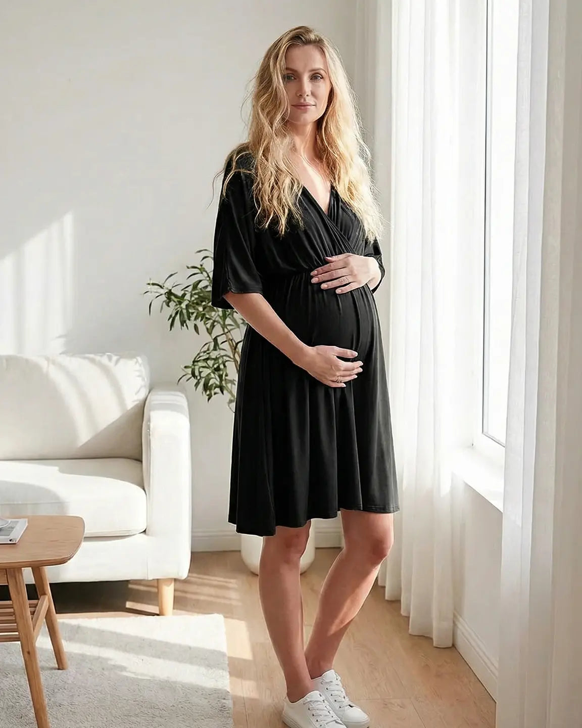 Pregnant woman in a black cross-front maternity midi dress with 3/4 sleeves, flattering her bump.