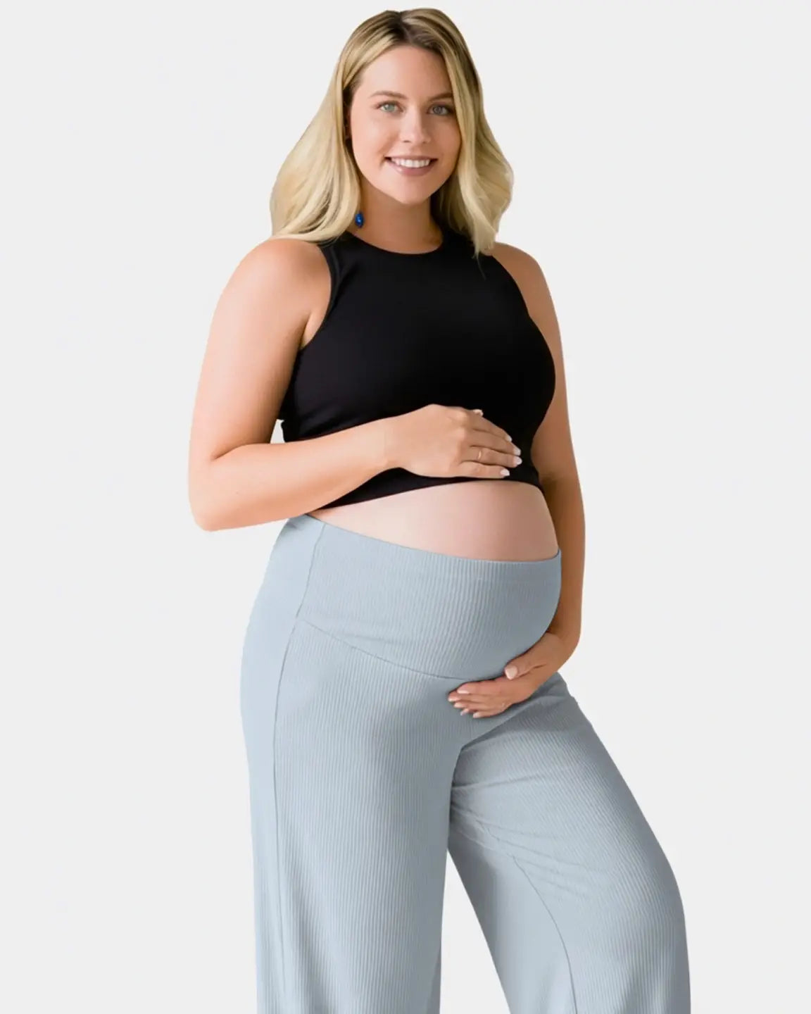 Smiling pregnant woman in light blue ribbed wide-leg maternity pants with an over-bump waistband.