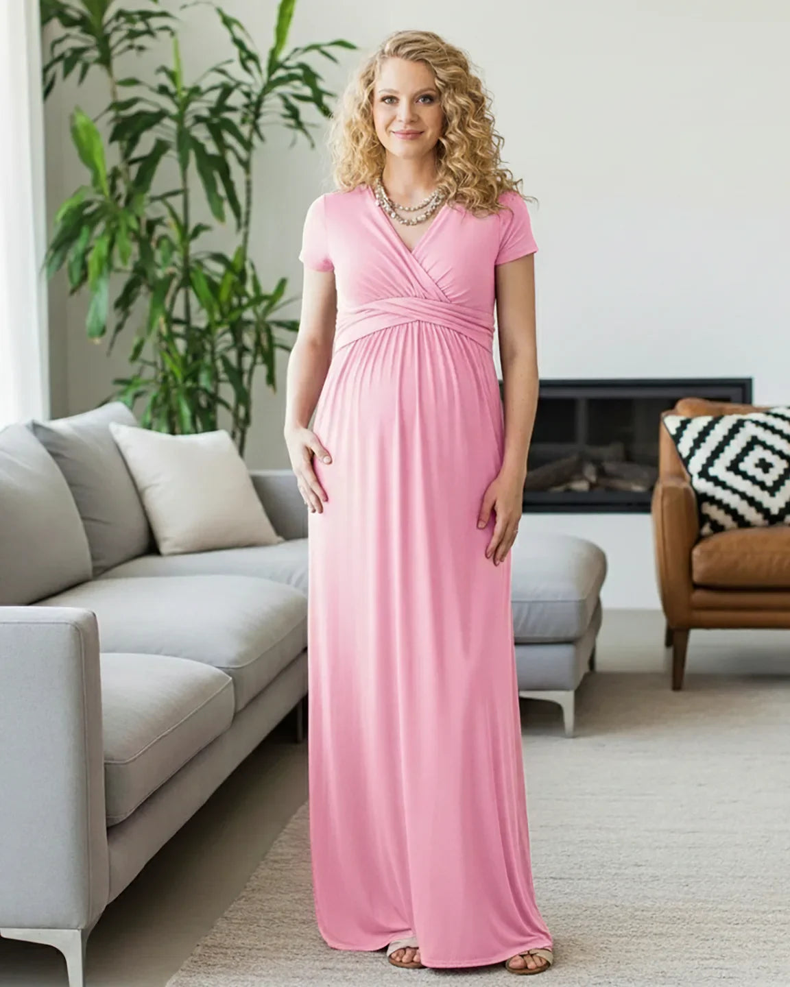 Blonde pregnant woman in a pink twist-front draped maternity nursing maxi dress with short sleeves.