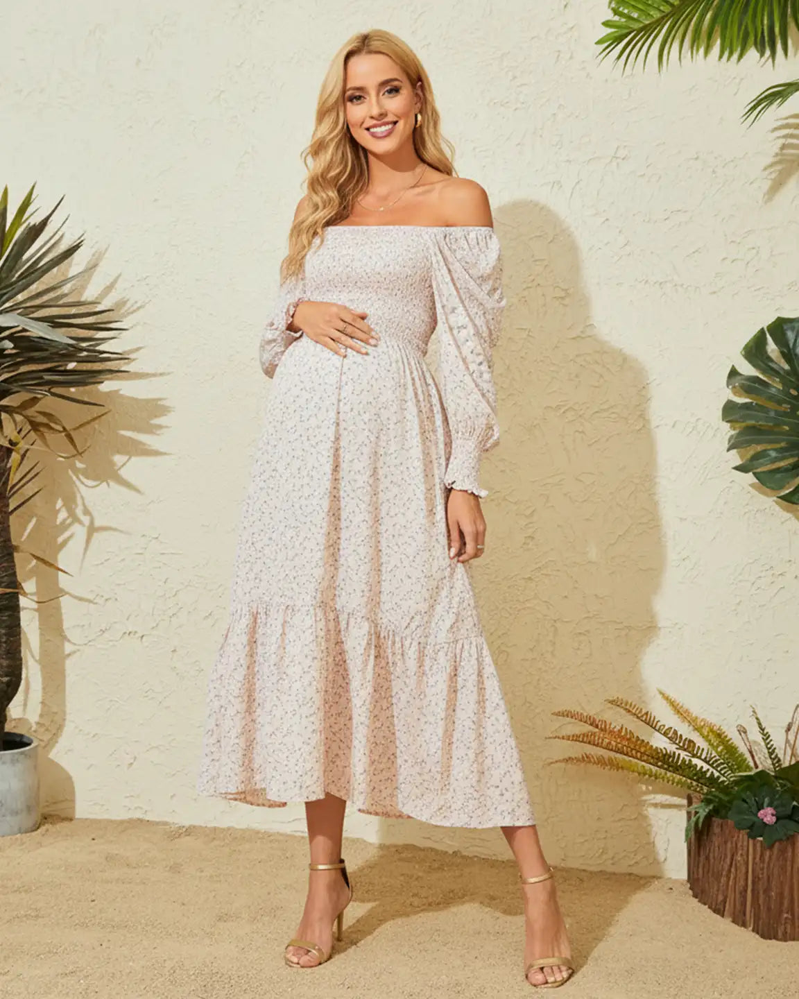 Maternity model in a light pink off-shoulder floral midi dress with smocked bodice and tiered skirt.