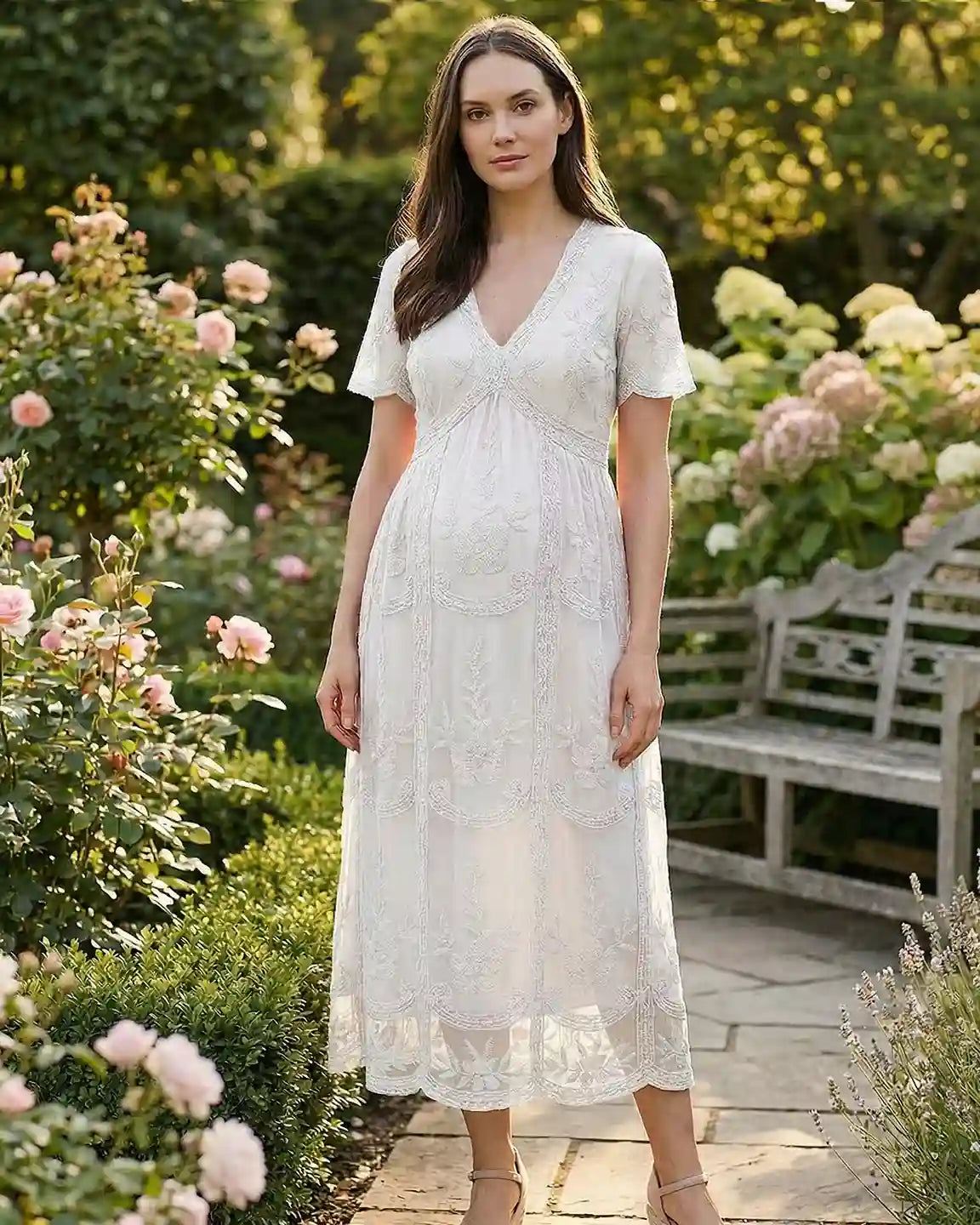 White lace maternity midi dress with V-neck, short sleeves, and swing skirt, worn by a pregnant woman in a garden.