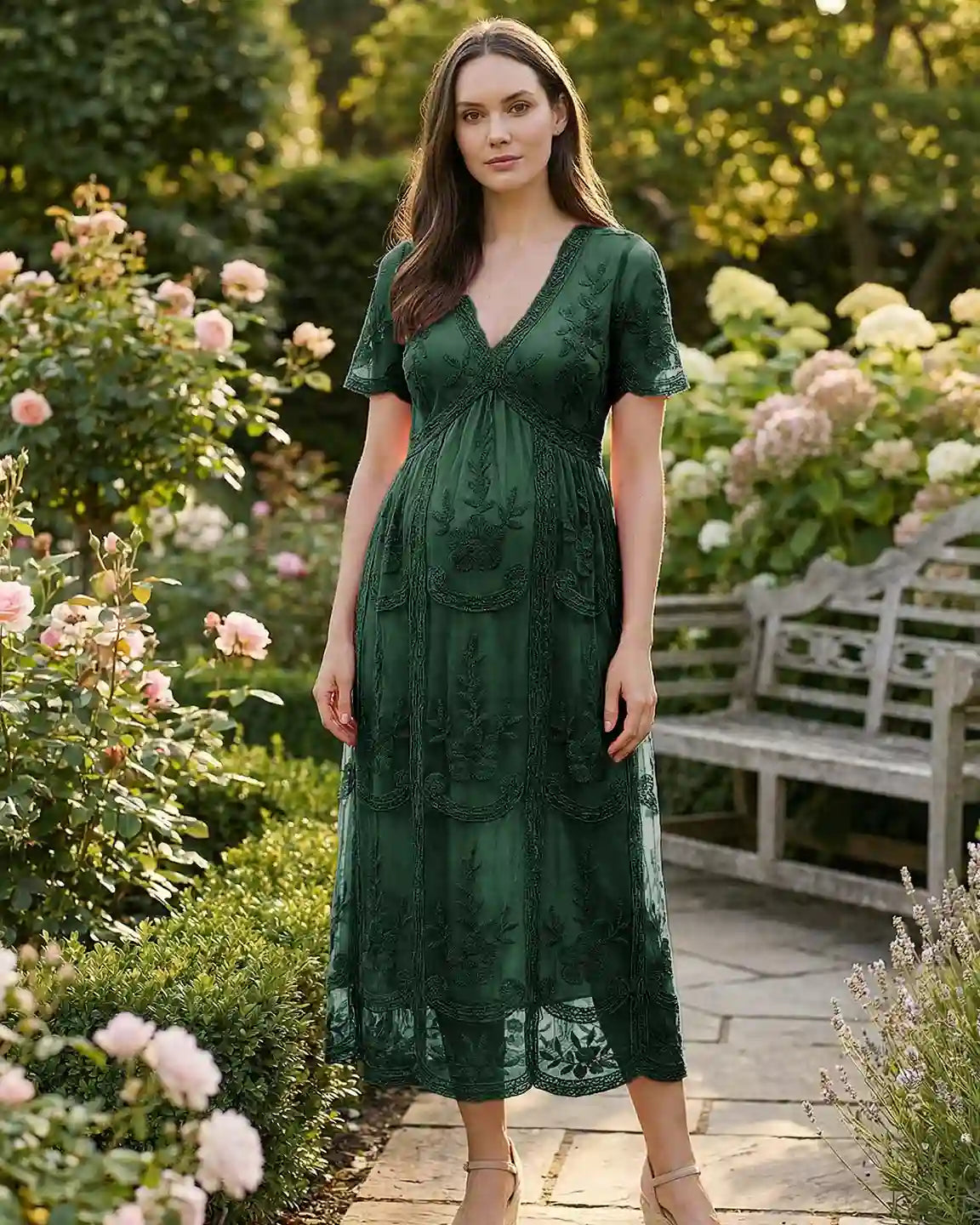 Maternity midi dress in dark green lace with V-neck, three-quarter sleeves, and swing skirt, worn in a garden.