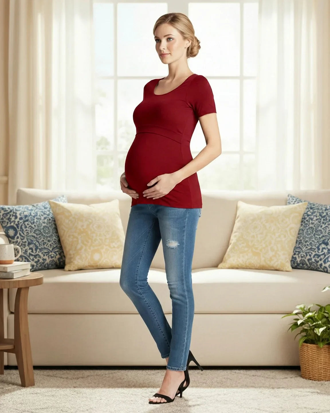 Pregnant woman in a red stretch-fit V-neck nursing t-shirt and jeans, hands on belly.