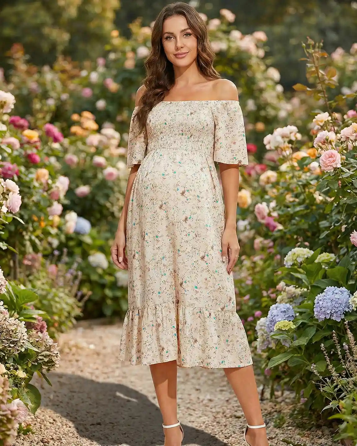 Maternity midi dress with flutter sleeves, smocked top, and floral print, worn by a pregnant woman in a garden.