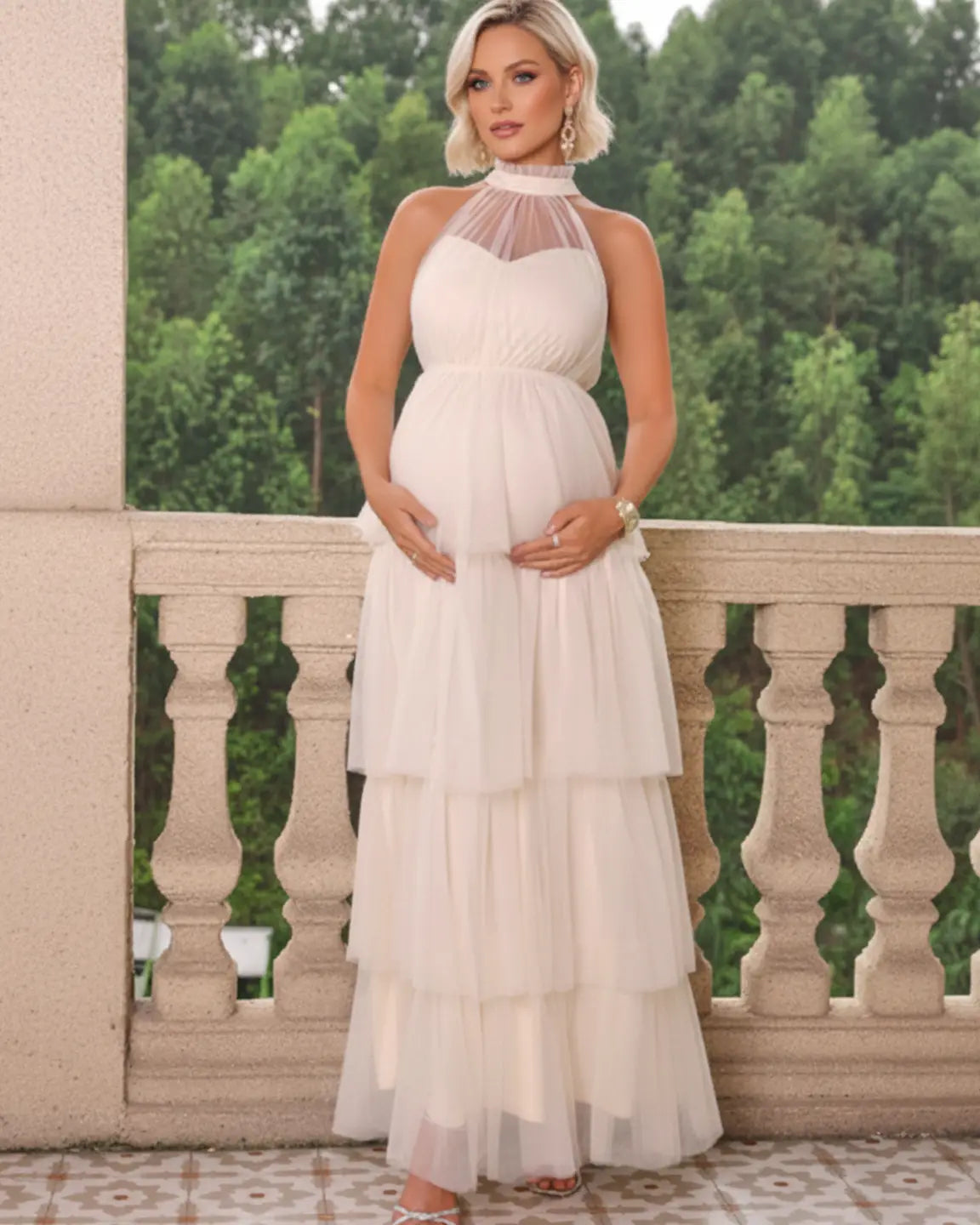 Maternity model in a white halter neck tiered mesh gown, showcasing a romantic, cloud-like skirt.