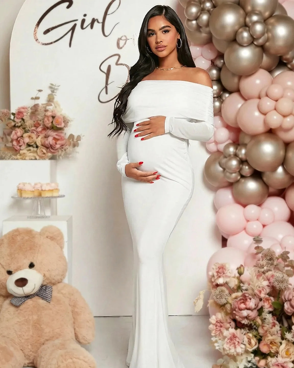 Pregnant woman in a white off-shoulder draped neck mermaid fit maternity maxi dress, cradling her bump.