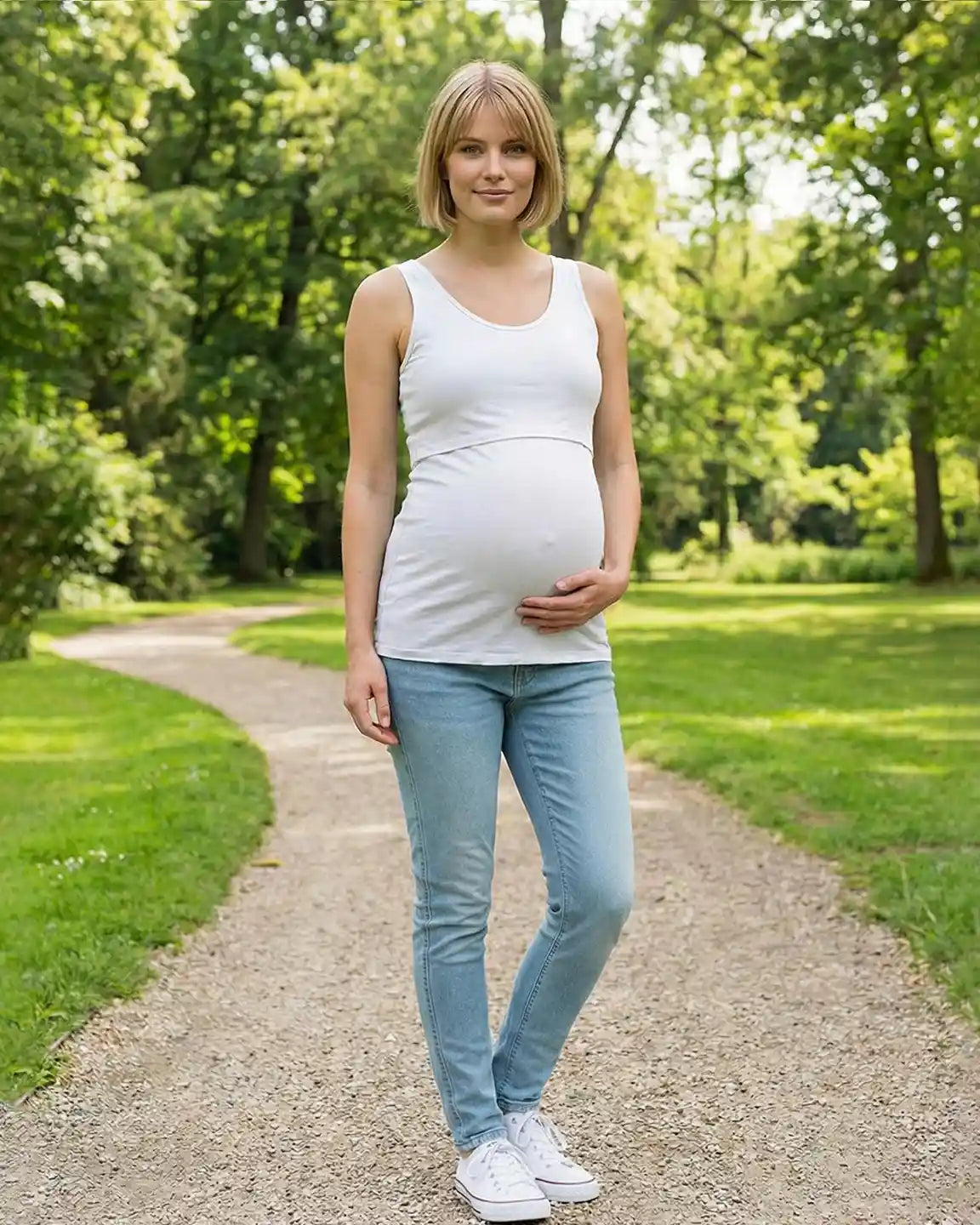 Pregnant woman in a white stretch nursing-access maternity tank top and light blue jeans.