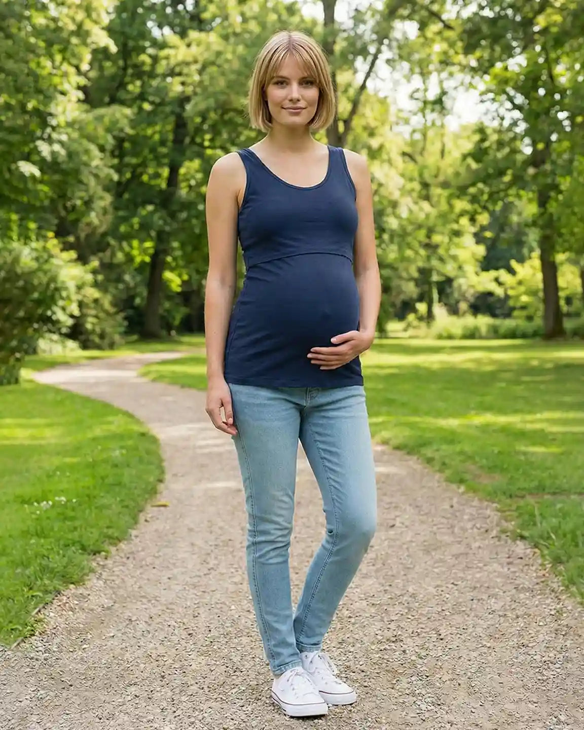Pregnant woman in a navy stretch nursing-access maternity tank top and light wash jeans.