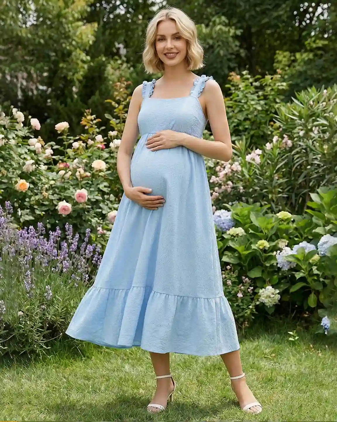 Smiling pregnant woman in a light blue ruffled strap maternity maxi dress with a tiered skirt.