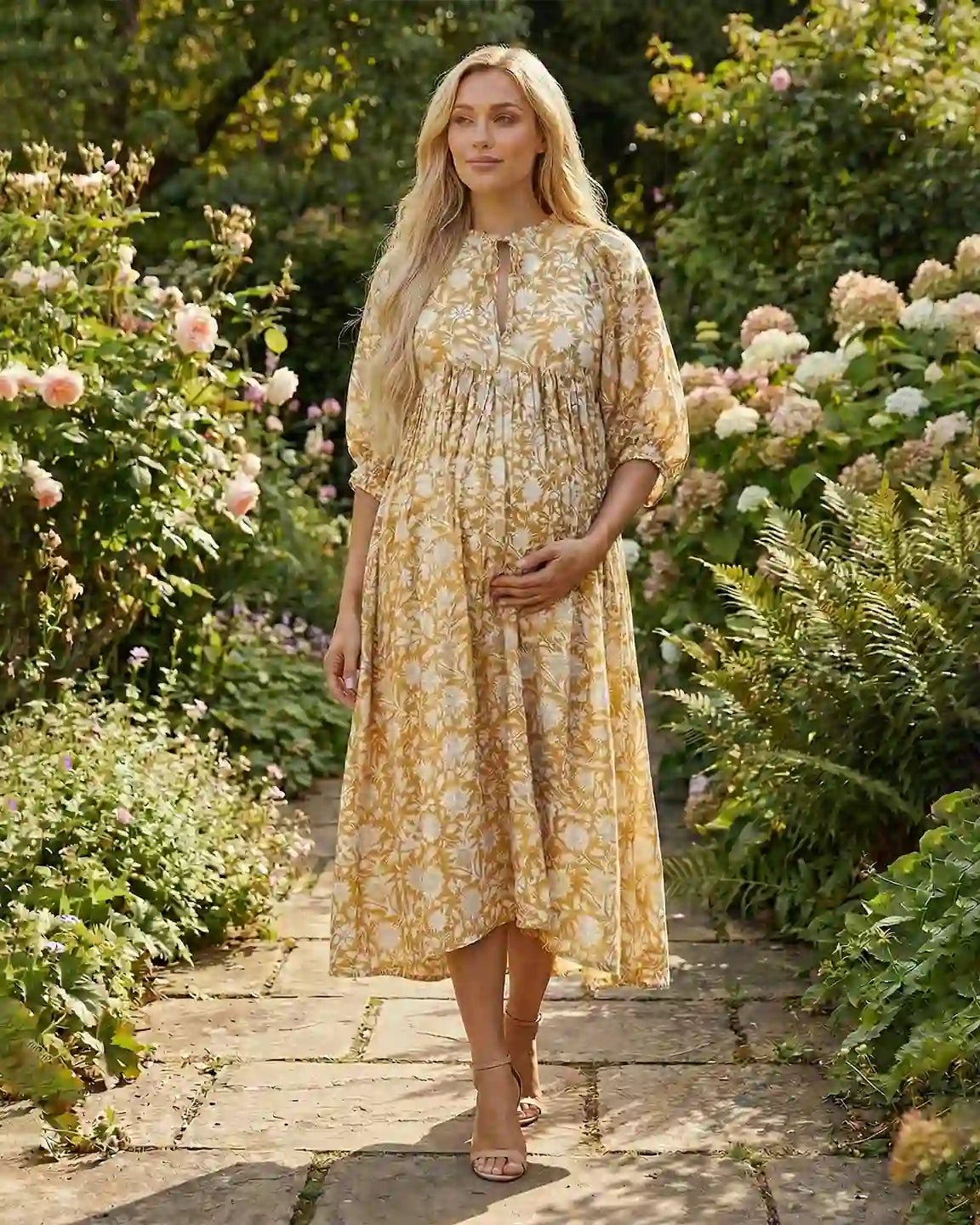 Blonde pregnant woman in a yellow floral loose-fit maternity midi dress with gathered shoulders and puff sleeves.