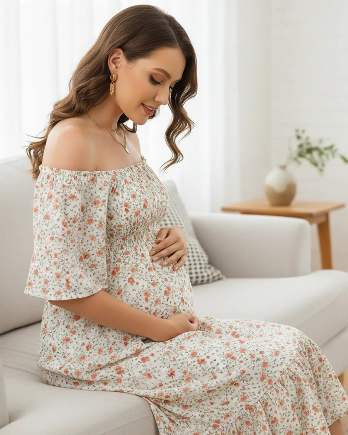 Maternity midi dress with white floral print, off-shoulder smocked top, flutter sleeves, and tiered skirt.