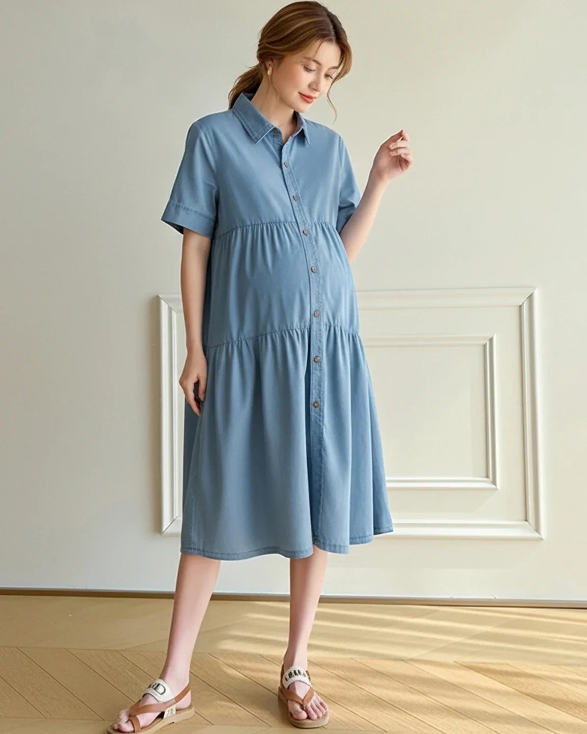 Maternity model wearing a blue tiered denim midi dress with short sleeves and button-front.