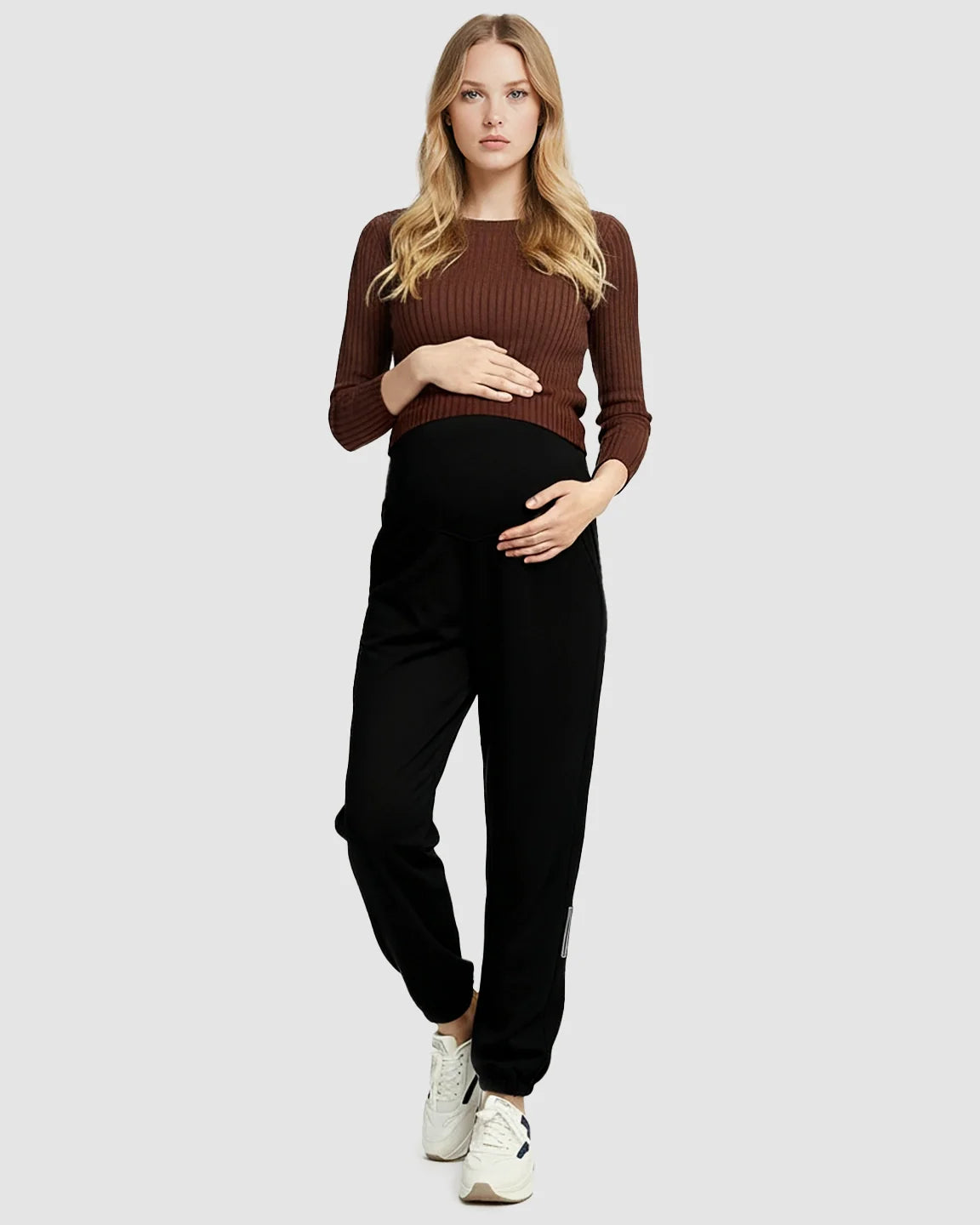 Woman in black soft knit maternity joggers with a supportive waistband and side pockets.