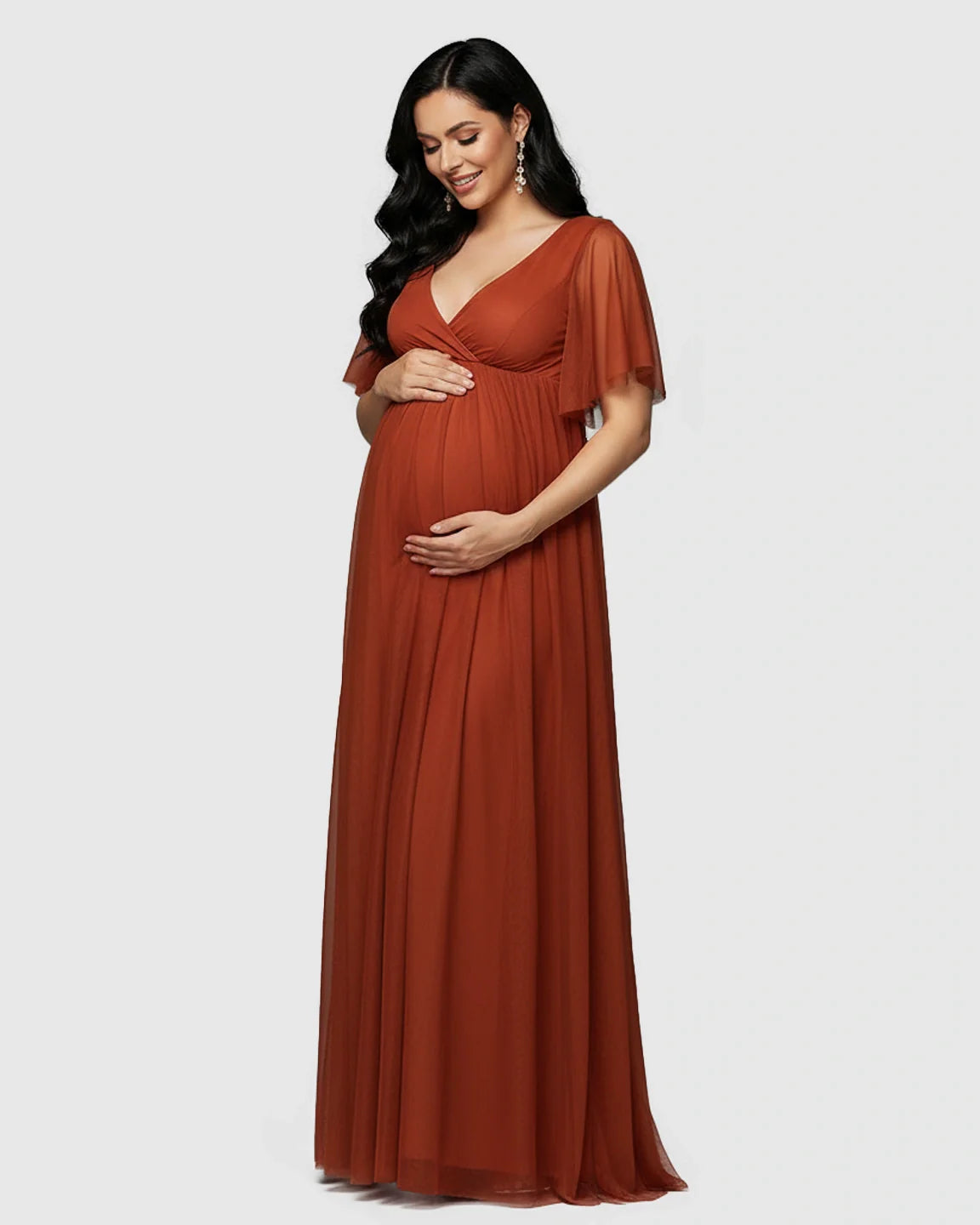 Pregnant woman in a rust V-neck chiffon empire waist maternity maxi dress with flutter sleeves.