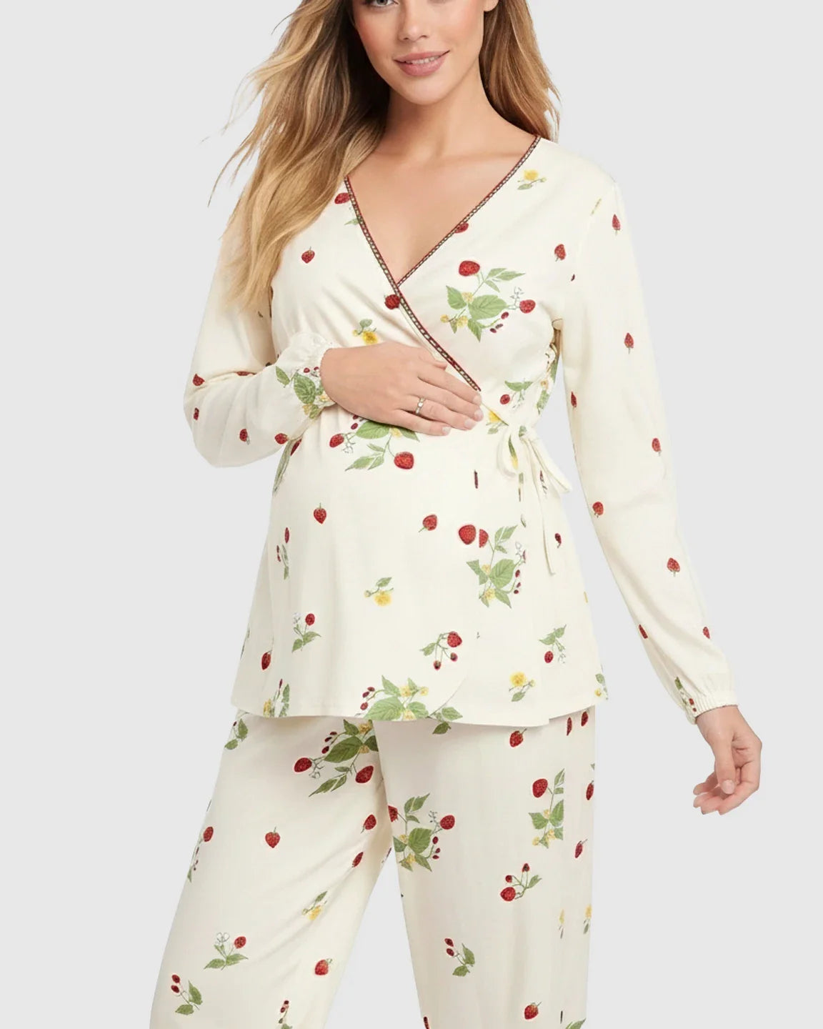 Pregnant woman in a cream floral wrap kimono style maternity pajama set with red strawberries.
