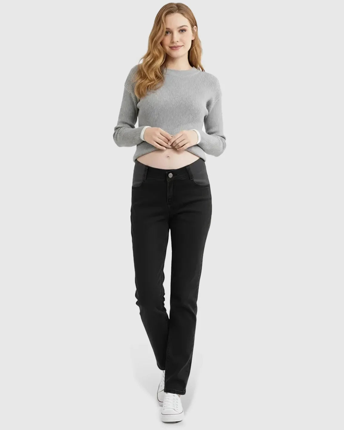 Smiling pregnant woman in black straight-leg maternity jeans with side panels and a gray ribbed sweater.