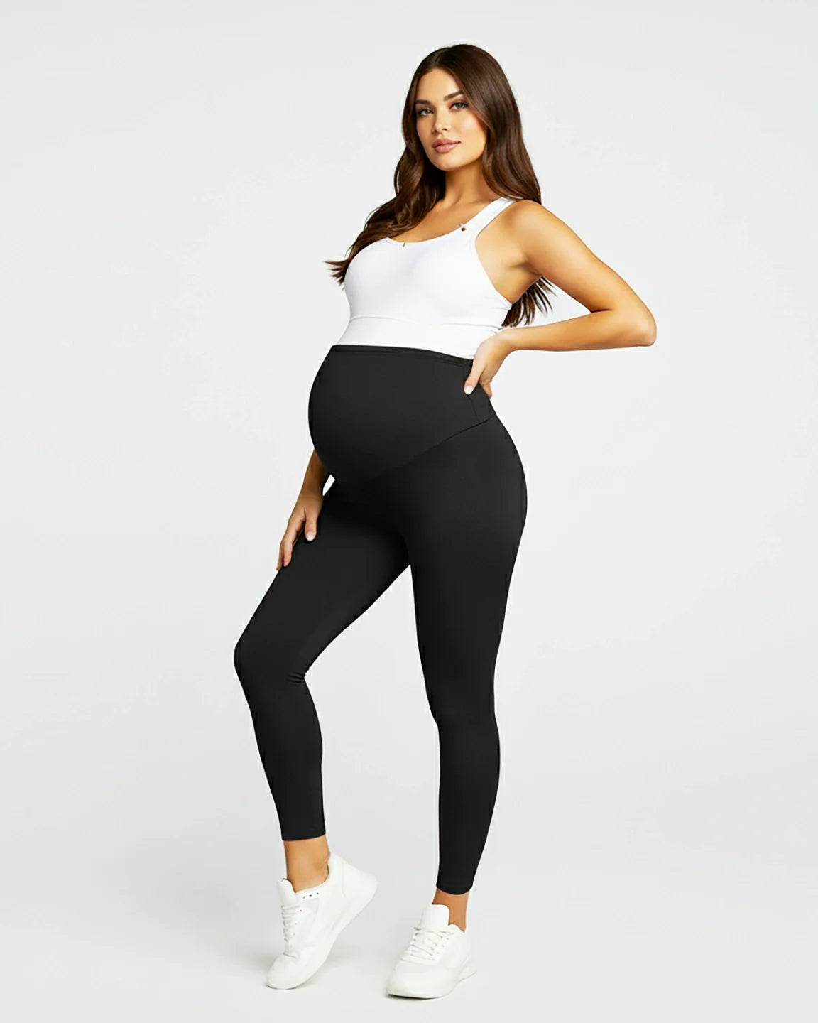 Pregnant woman in black sculpting ankle-length maternity leggings with a supportive over-the-bump panel.