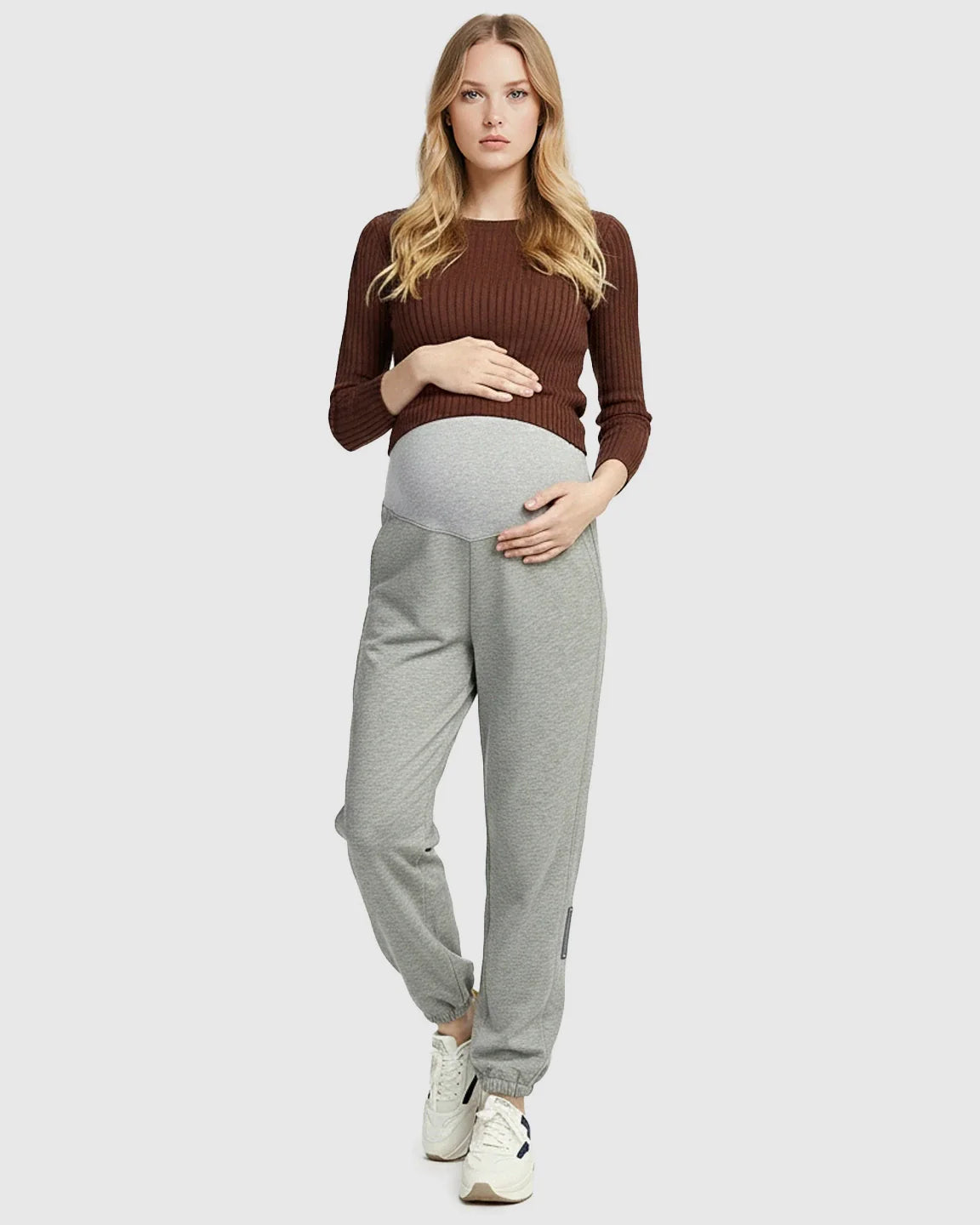 Pregnant woman in grey soft knit maternity joggers with a supportive waistband and side pockets.