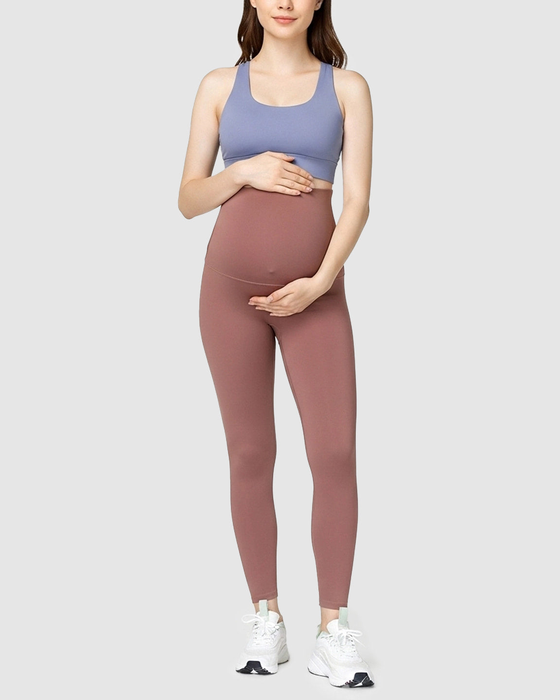 Pregnant woman wearing high-waist, soft stretch maternity leggings in dusty rose with a blue sports bra.