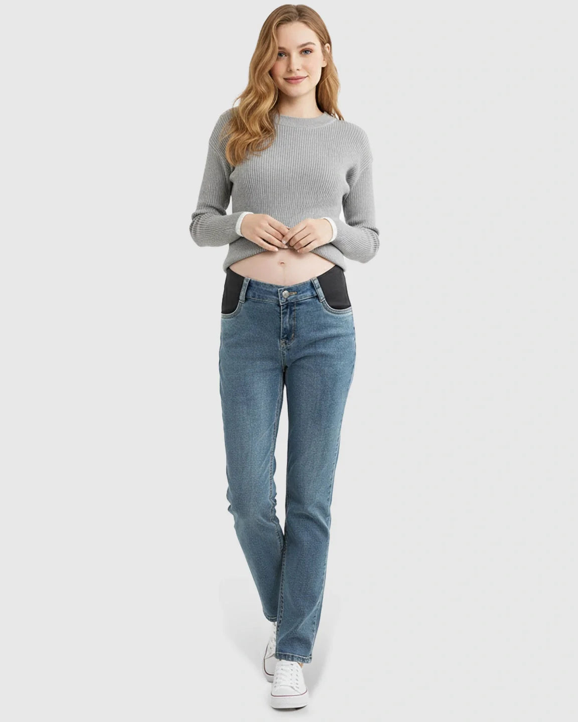 Woman in blue straight-leg maternity jeans with black side panels and a grey ribbed sweater.