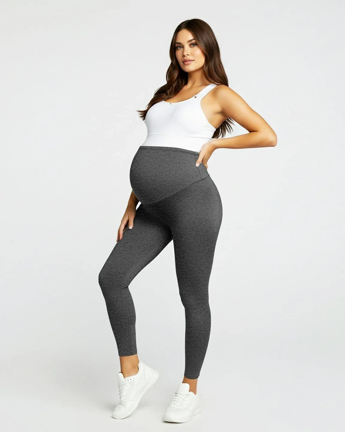Pregnant woman in dark grey sculpting ankle-length maternity leggings with an over-the-bump waistband.