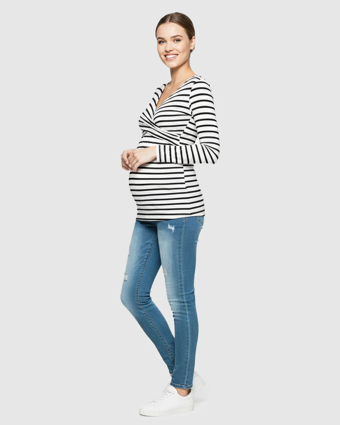 Smiling pregnant woman in a black and white striped long-sleeve V-neck maternity and nursing shirt.