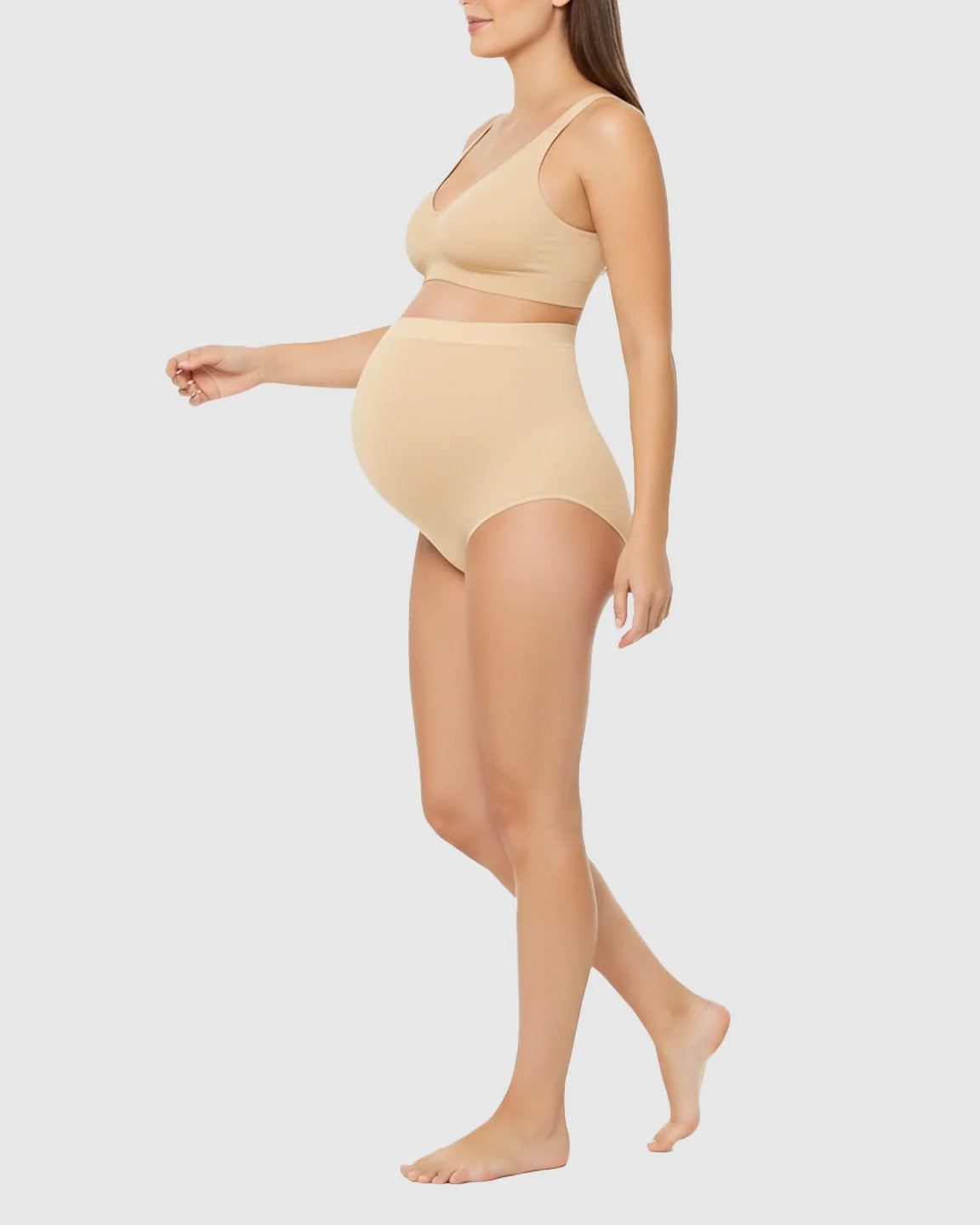 Pregnant woman in beige high-waist seamless belly-support maternity underwear and matching bra.
