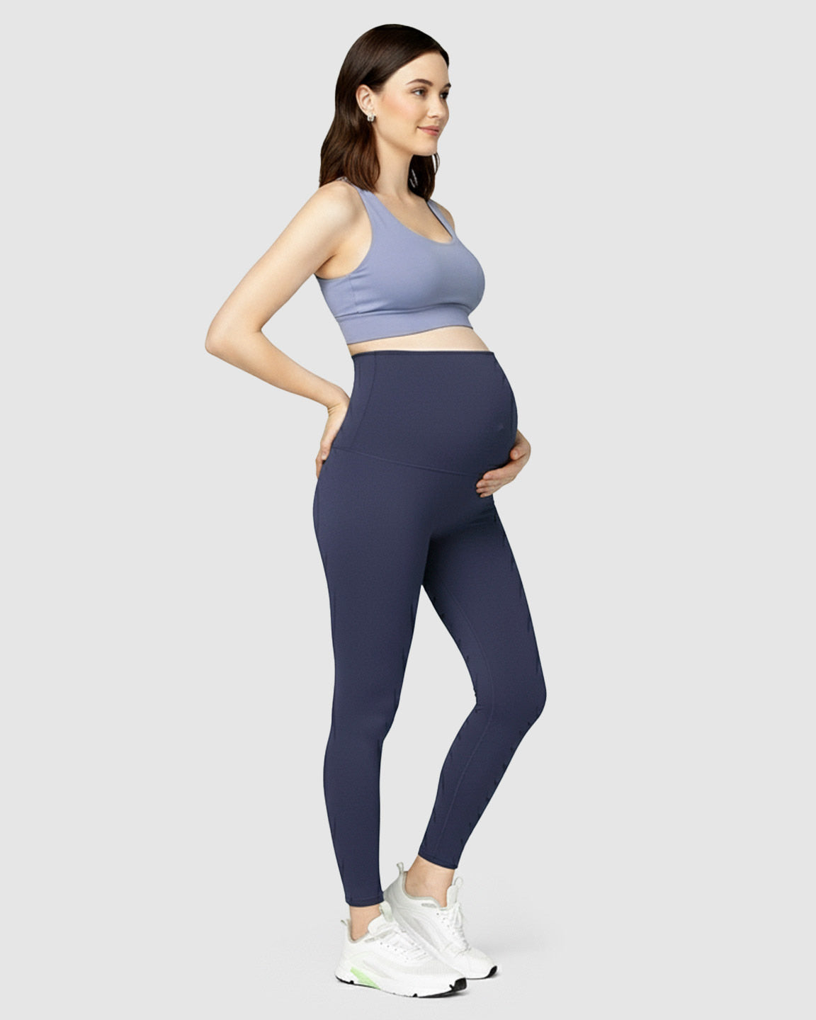 Pregnant woman wearing navy blue high-waist soft stretch maternity leggings and a periwinkle sports bra.