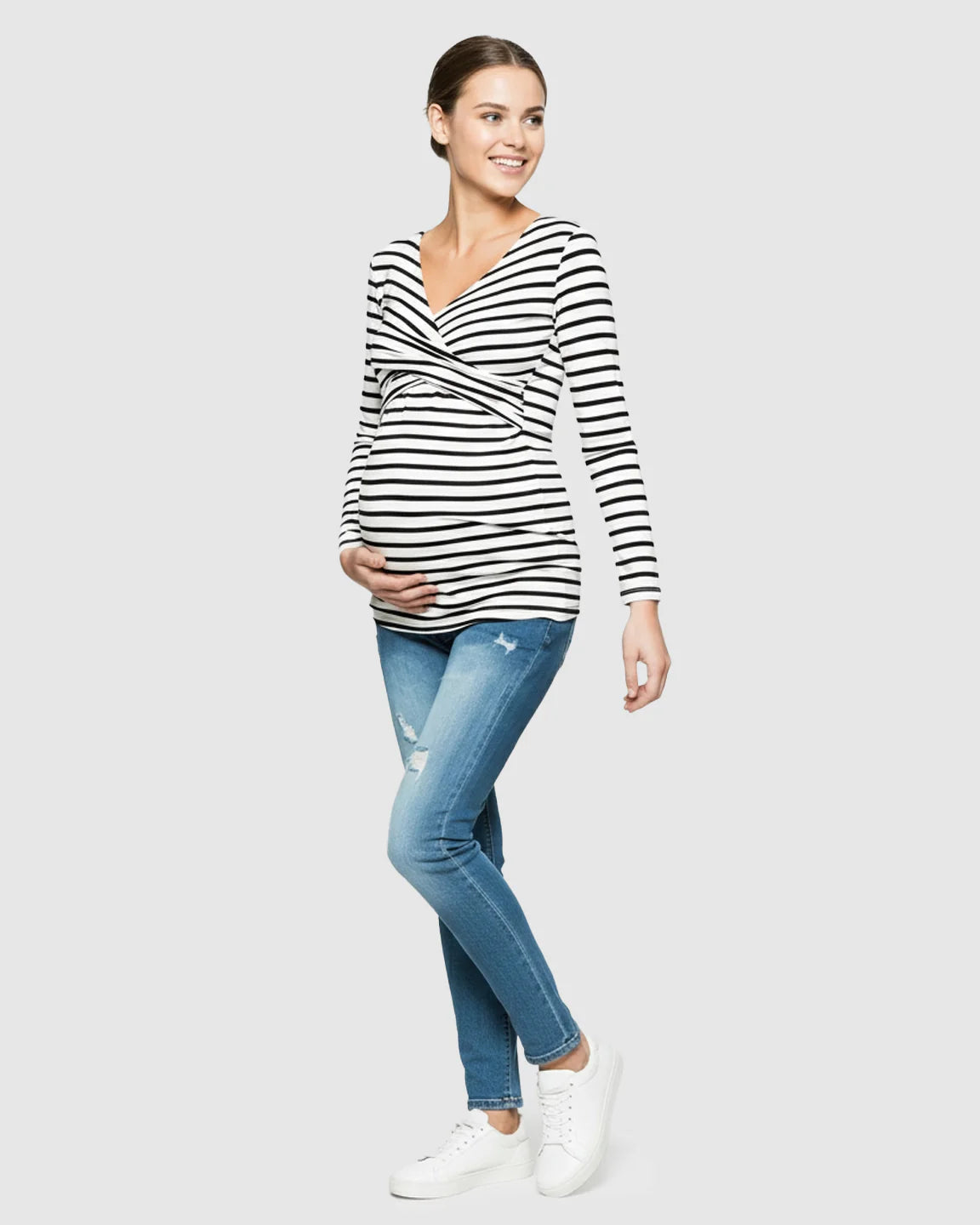 Smiling pregnant woman in a black and white striped long-sleeve V-neck maternity and nursing top.
