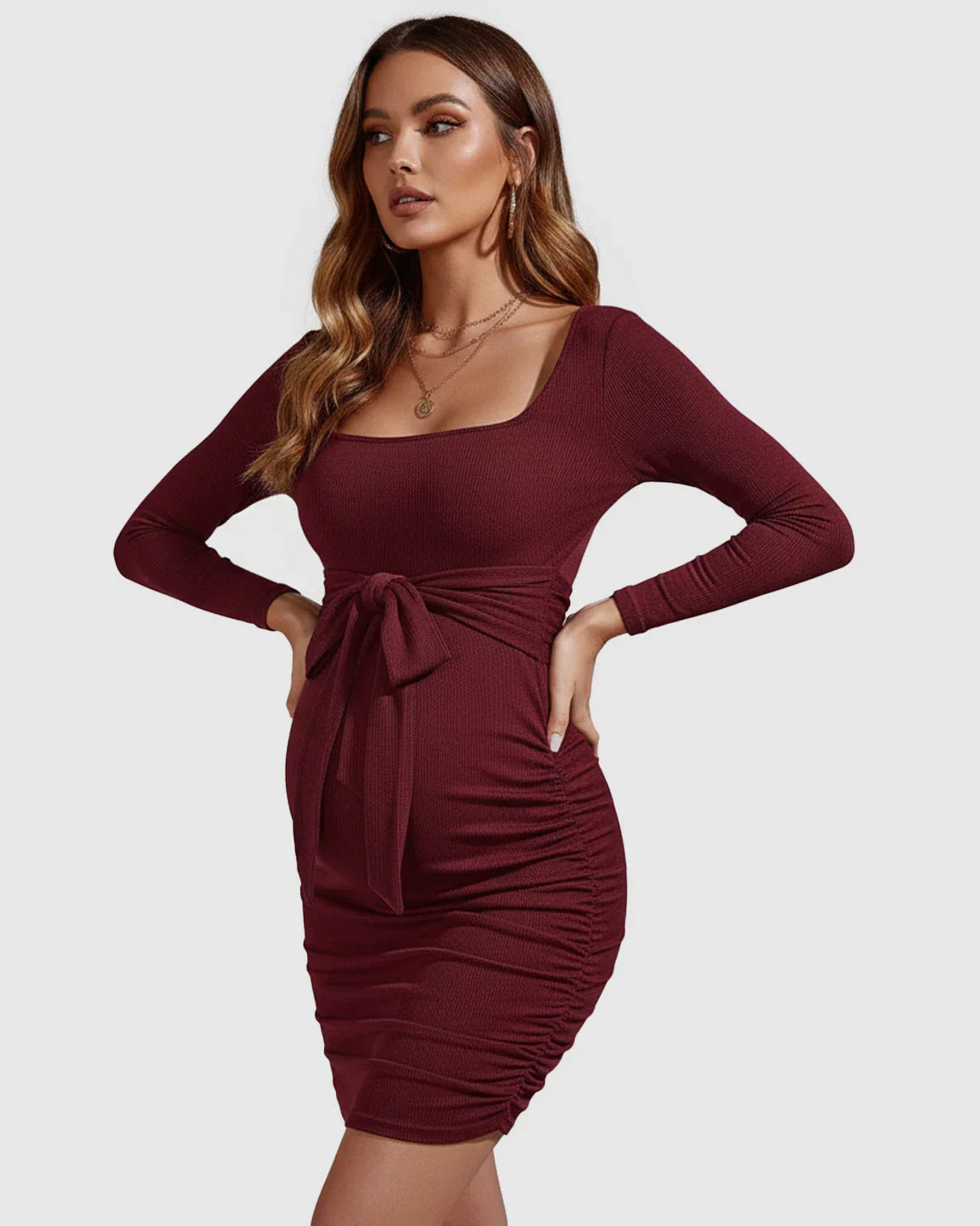 Burgundy long-sleeve maternity mini dress with square neckline, tie-waist, and side ruching.