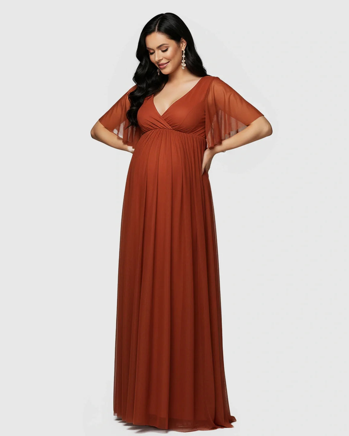 Rust chiffon V-neck empire waist maternity maxi dress with flutter sleeves, flowing gracefully over a pregnant belly.