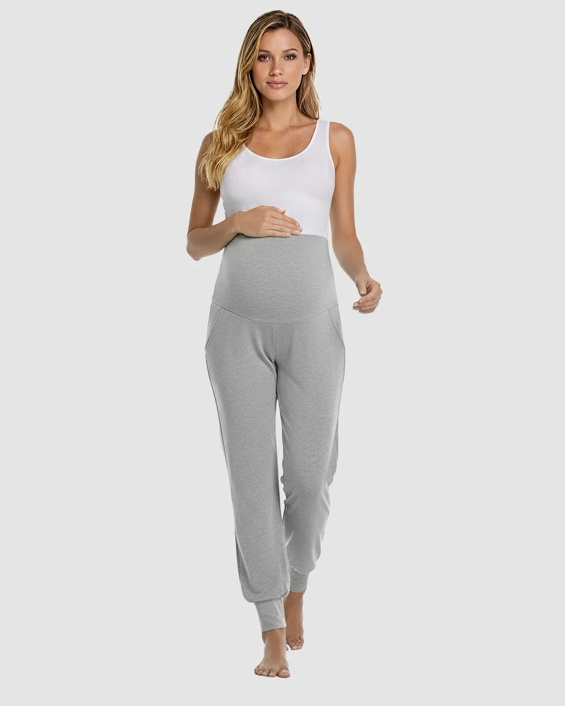 Woman in light gray ankle-cuffed maternity pants with an elastic waistband and pockets, paired with a white tank top.