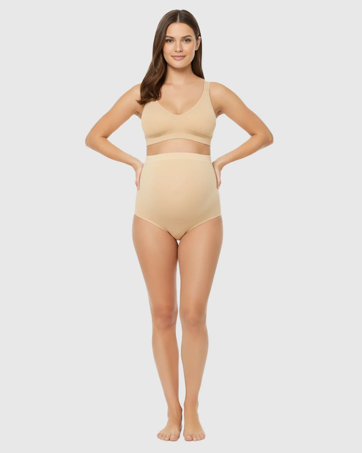 Smiling pregnant woman models seamless, high-waist nude maternity underwear and matching bra.