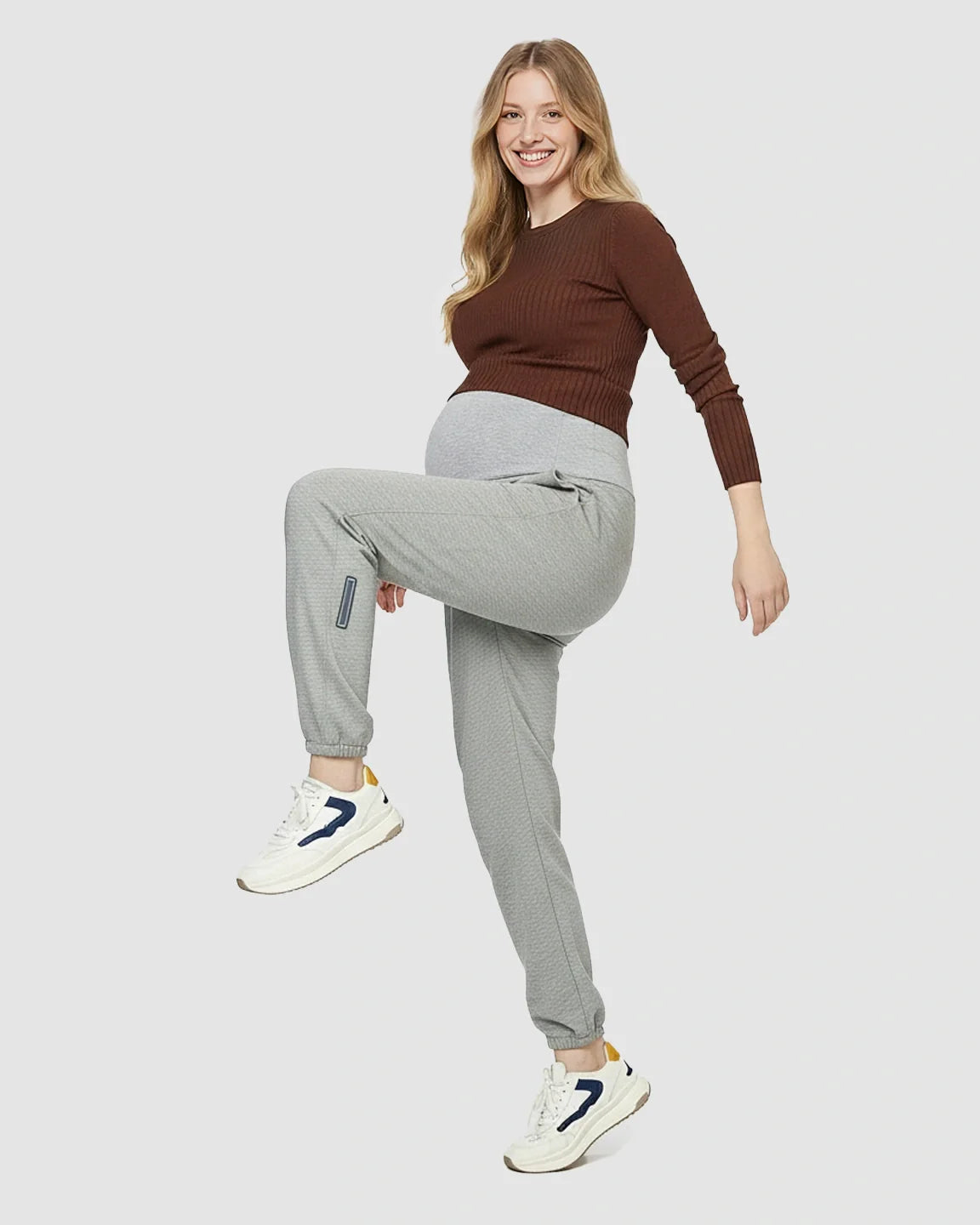 Smiling pregnant woman in grey soft knit pocketed maternity joggers with a supportive waistband.