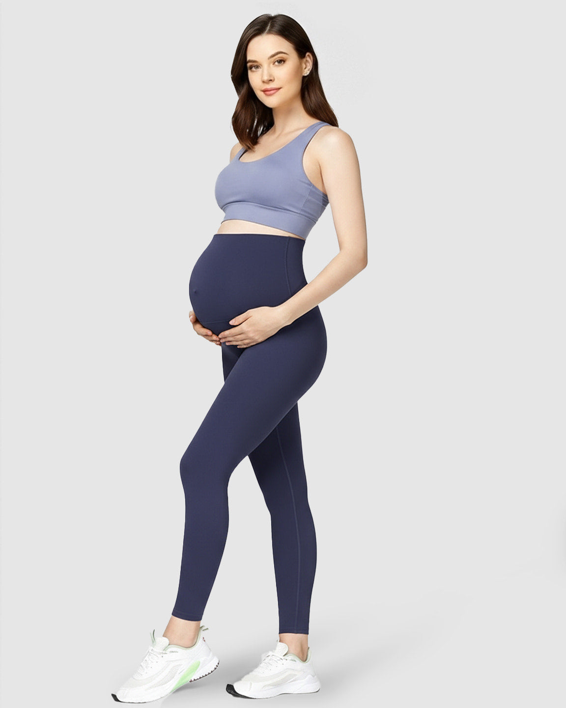 Smiling pregnant woman in navy high-waist soft stretch maternity leggings and a blue sports bra.