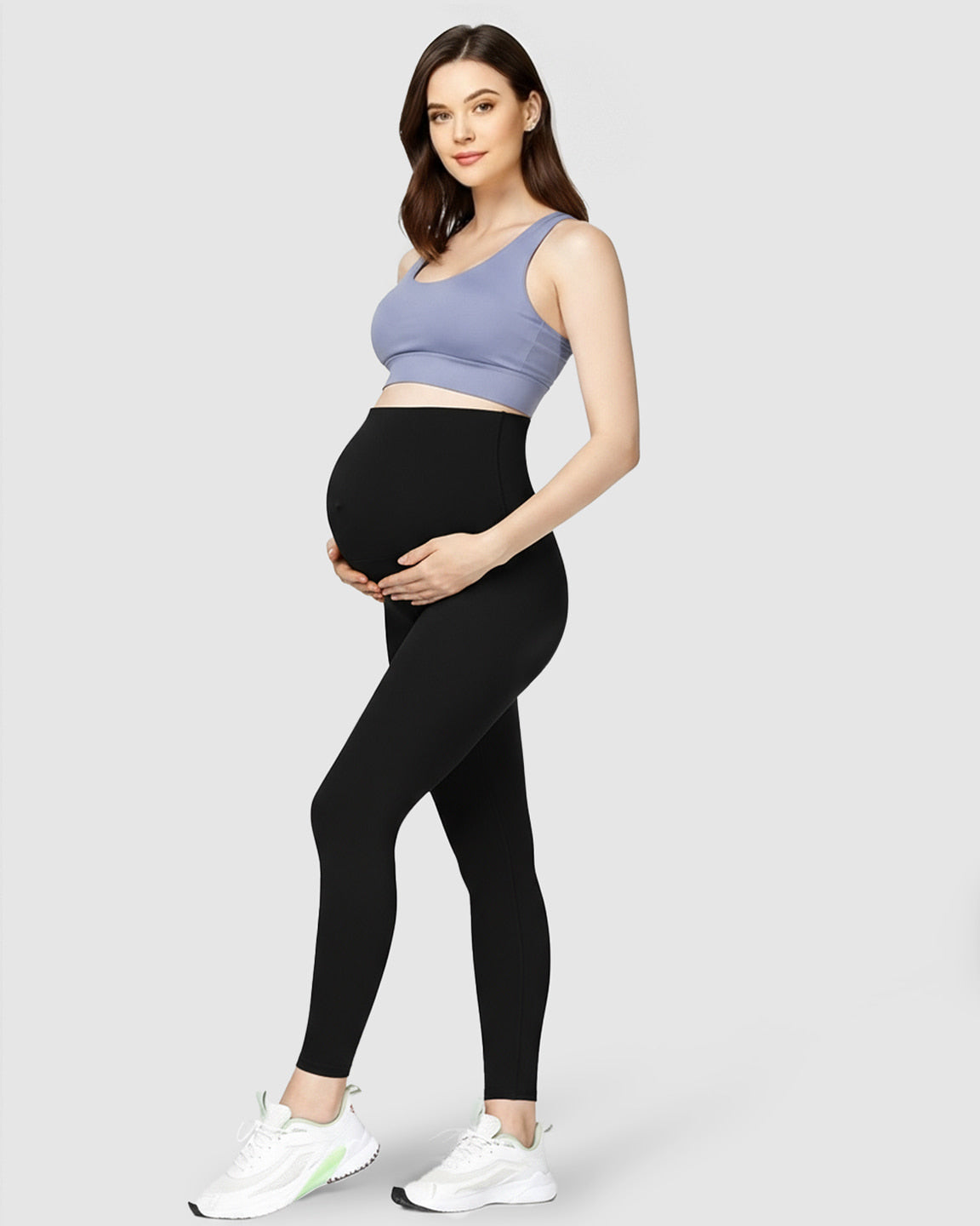 Pregnant woman in black high-waist soft stretch maternity leggings and a blue sports bra.